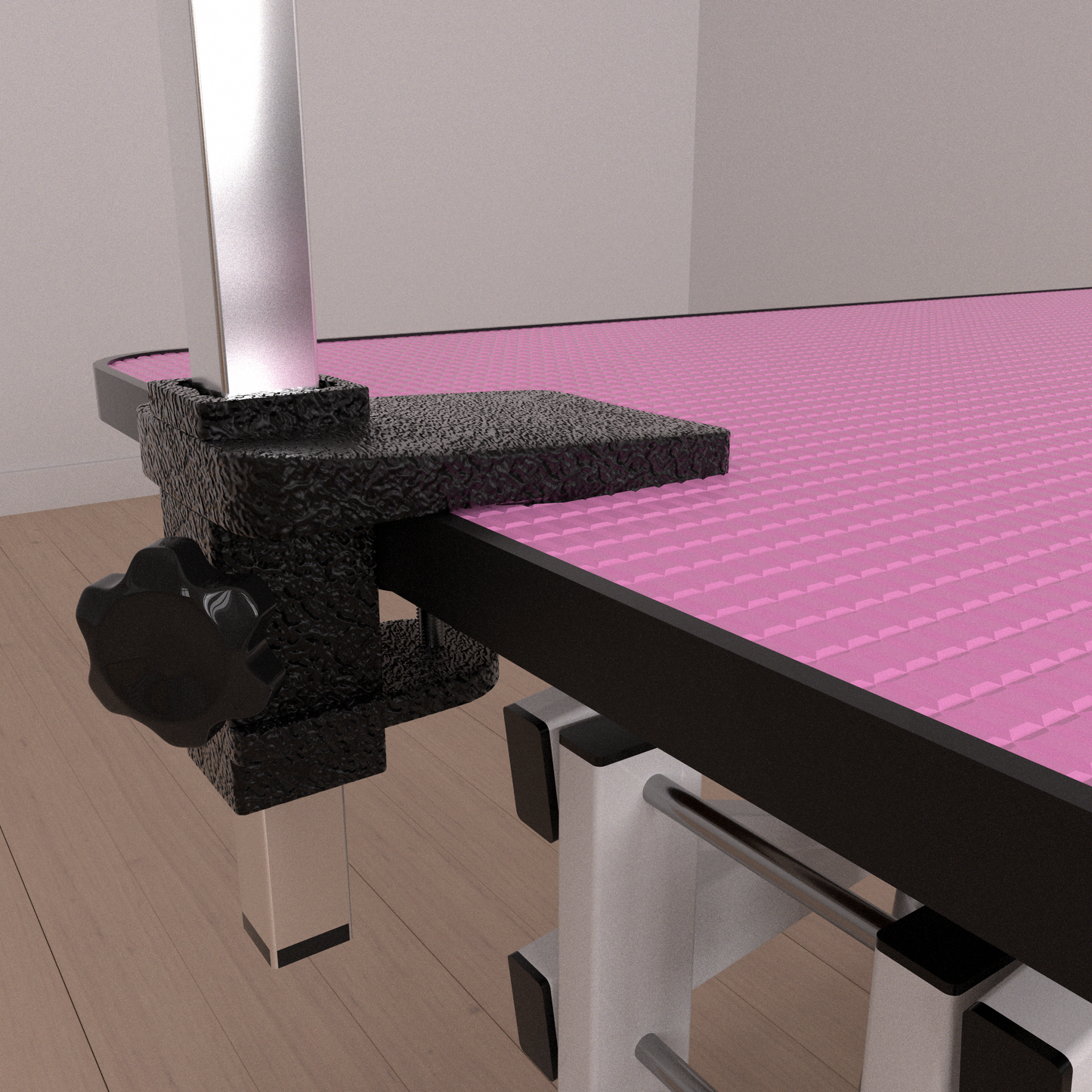 Closeup of a black adjustable clamp on a grooming table with a pink textured surface
