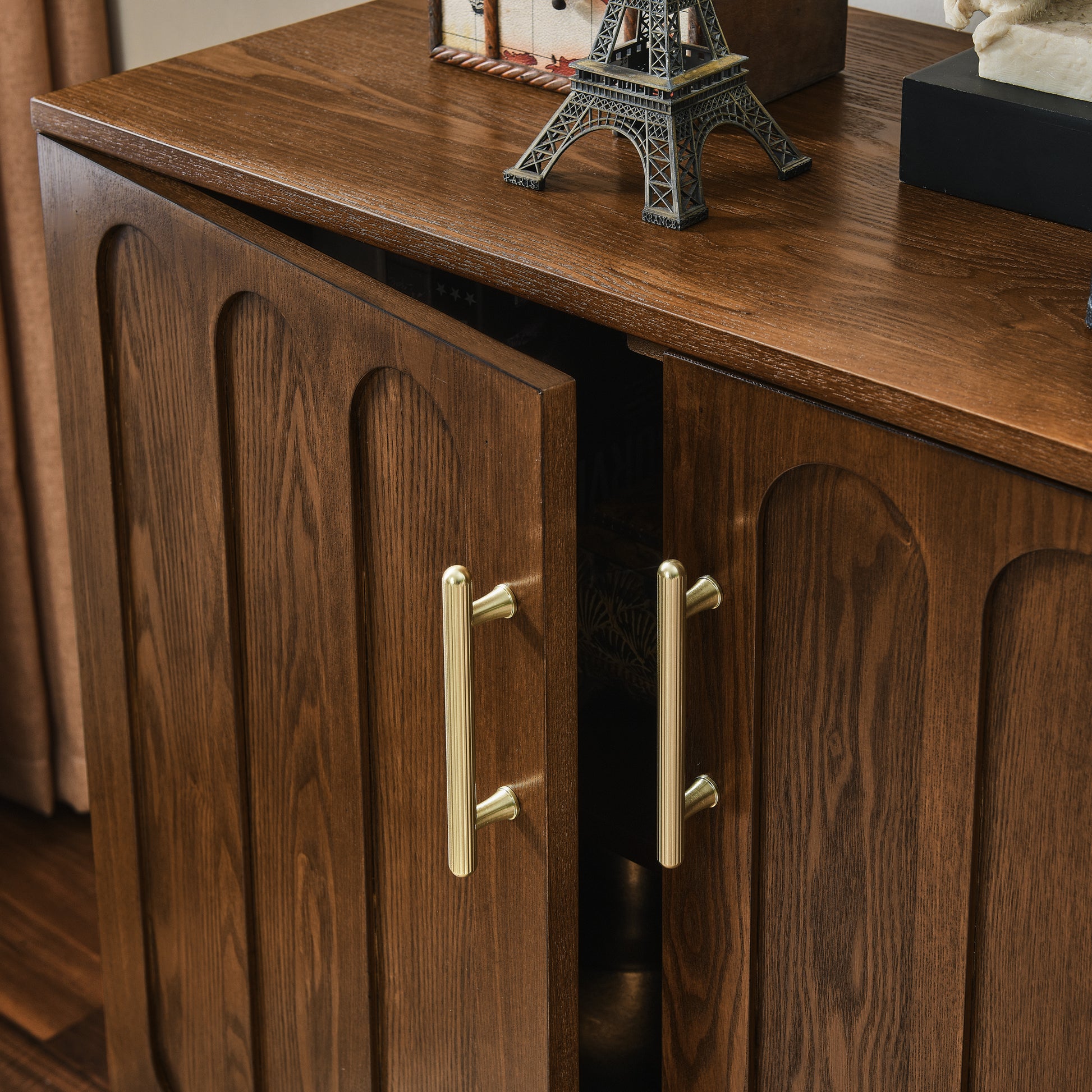 Dark wood cabinet with arched door panels and polished brass handles