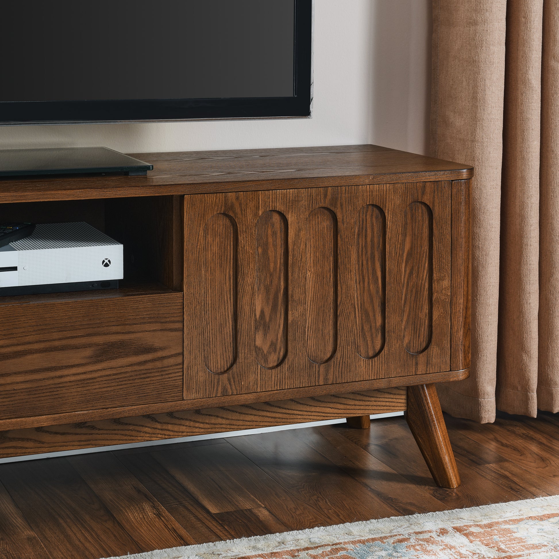 Midcentury modern oak TV stand with carved door panel and tapered legs