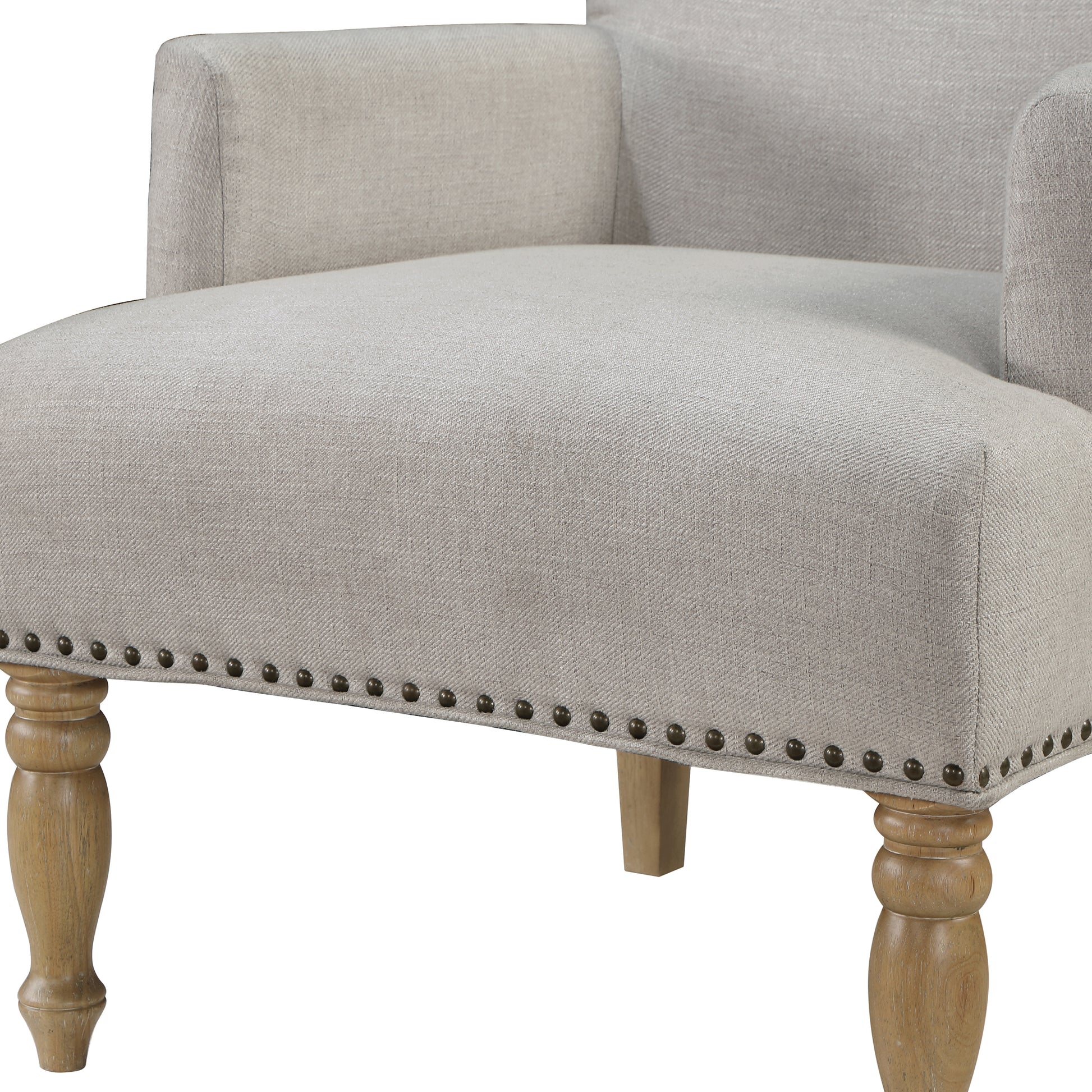 Beige upholstered accent chair with decorative nailhead trim and turned wooden legs
