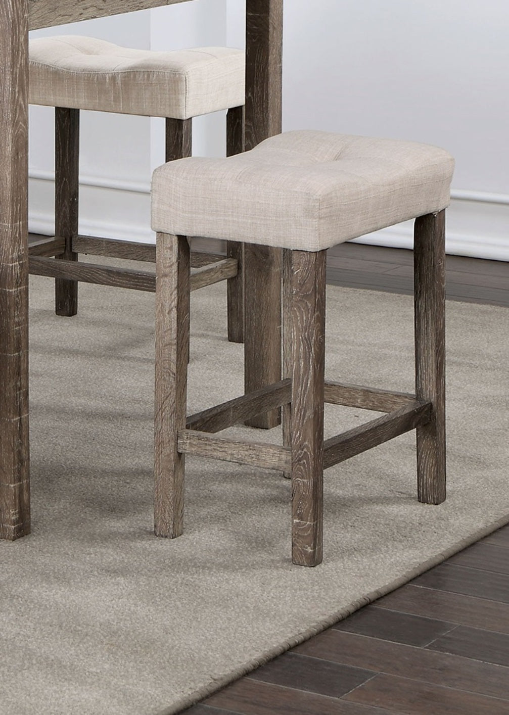Upholstered beige bar stool with a contoured seat and a distressed wood frame