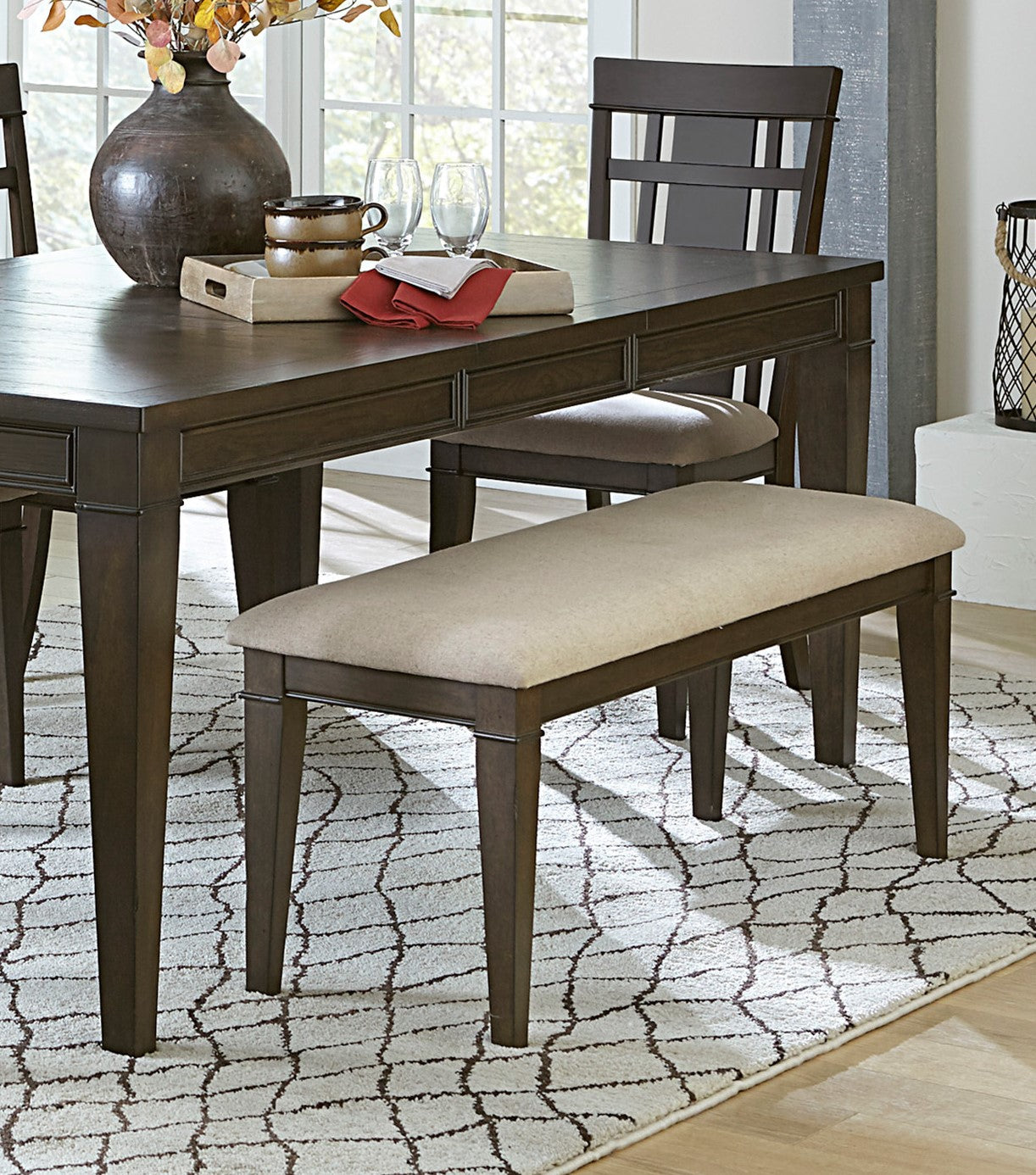 Dark wood dining table with a cream upholstered bench perfect for modern dining rooms