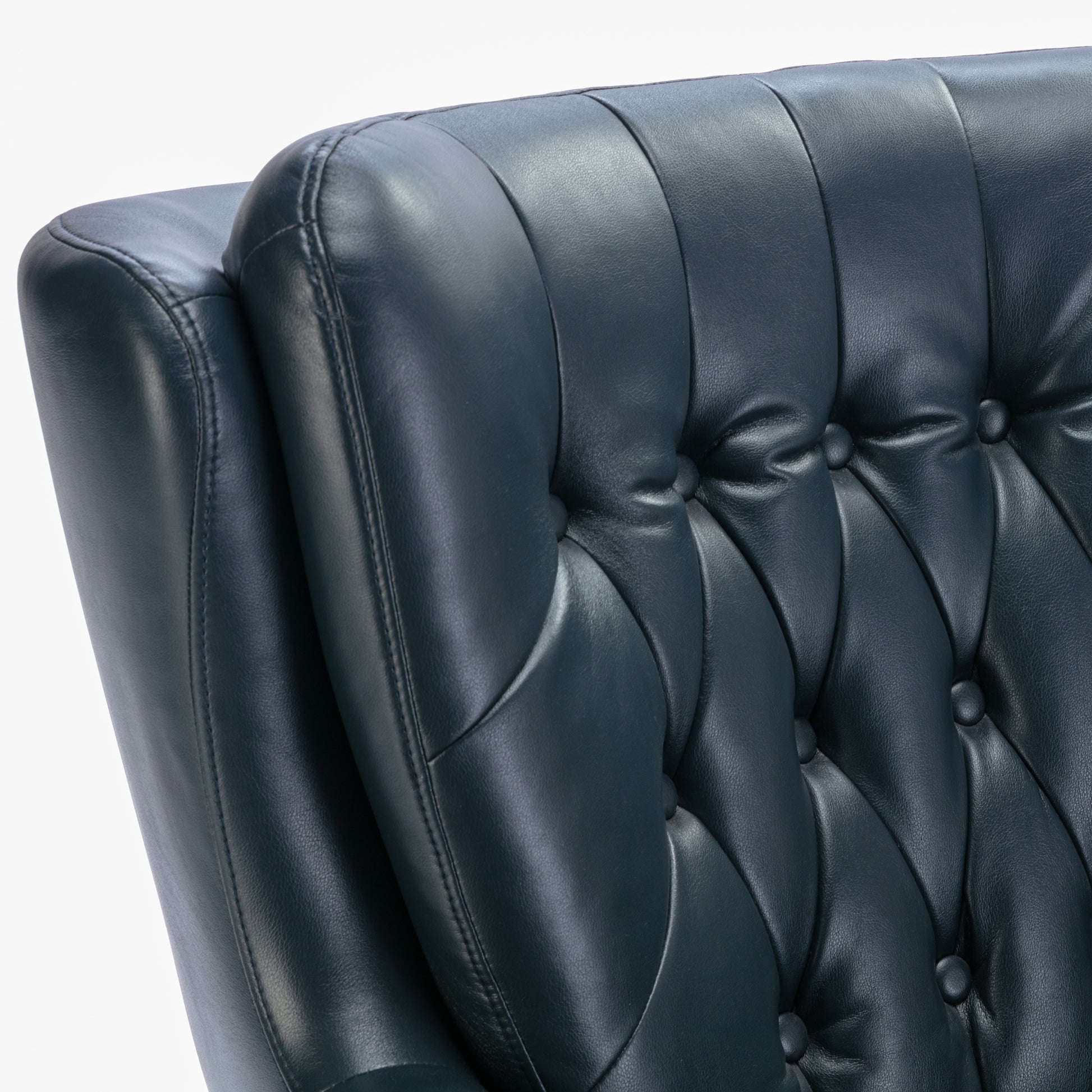 Closeup of tufted dark blue leather armchair back with button details