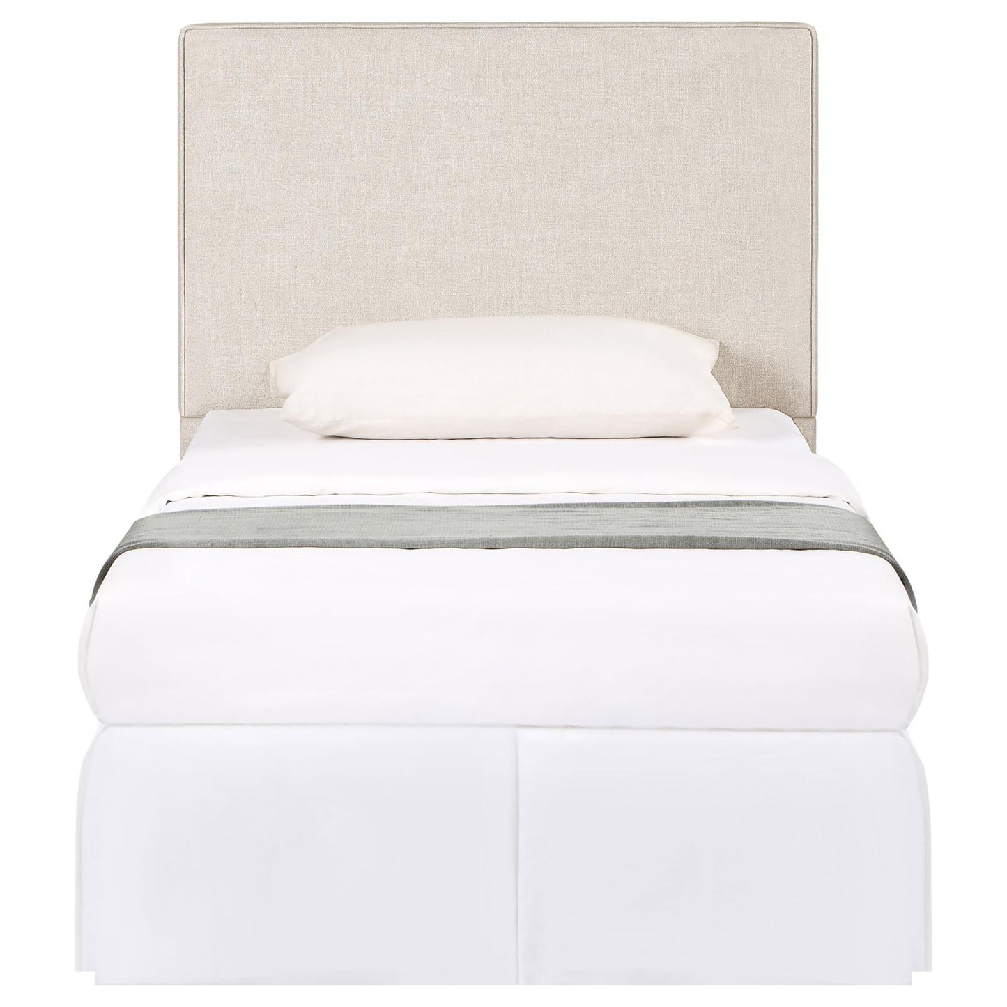 Beige upholstered headboard twin bed with white bedding and a grey throw
