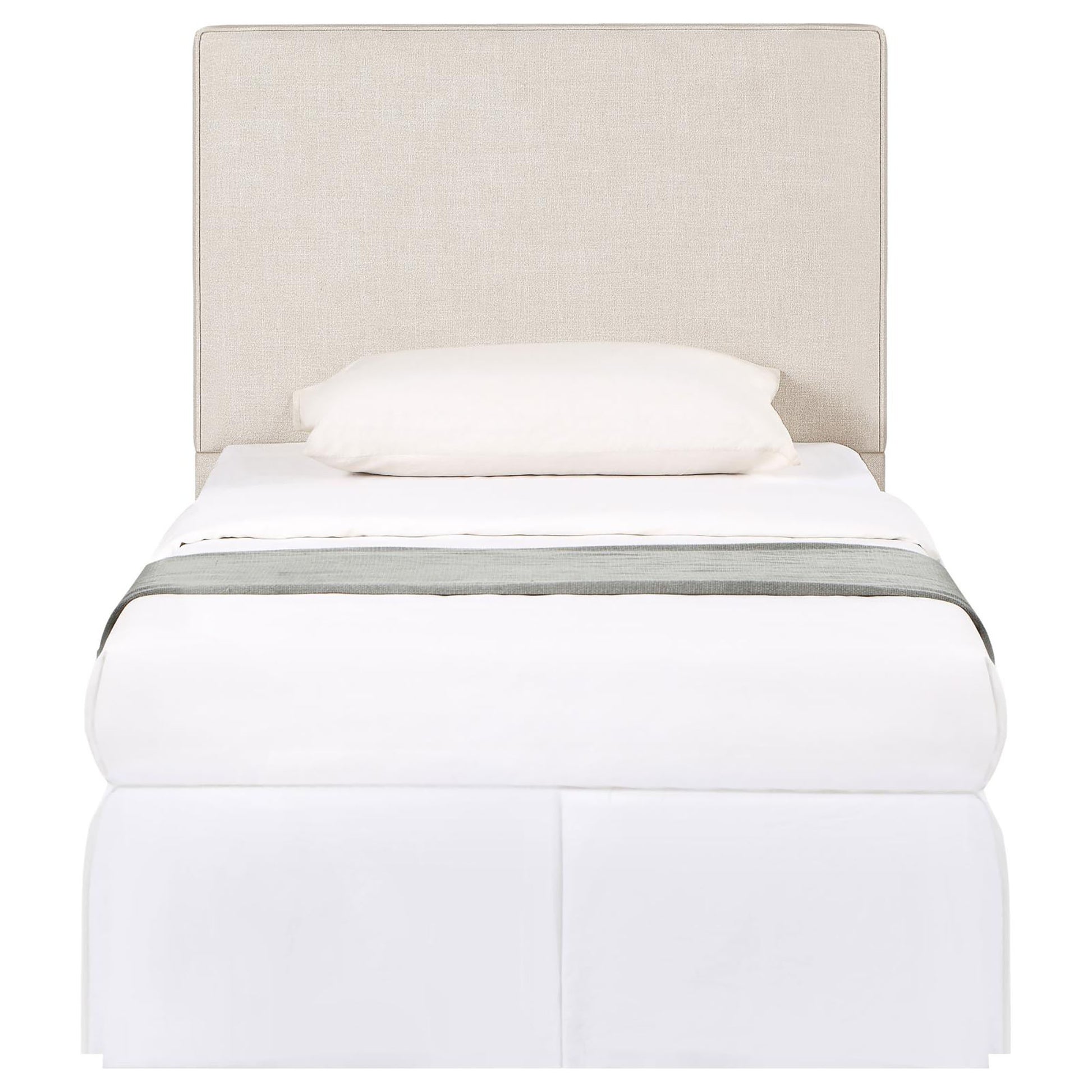 Beige upholstered headboard twin bed with white bedding and a grey throw