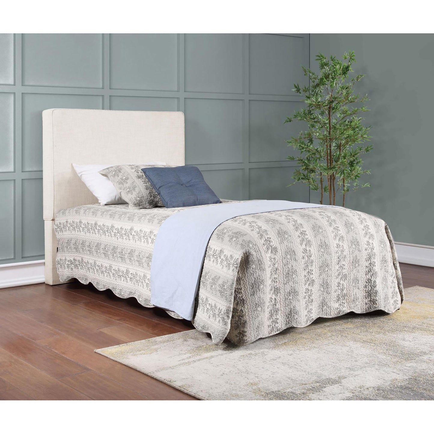 Beige upholstered headboard with a patterned quilt and blue accent pillow on a twin bed