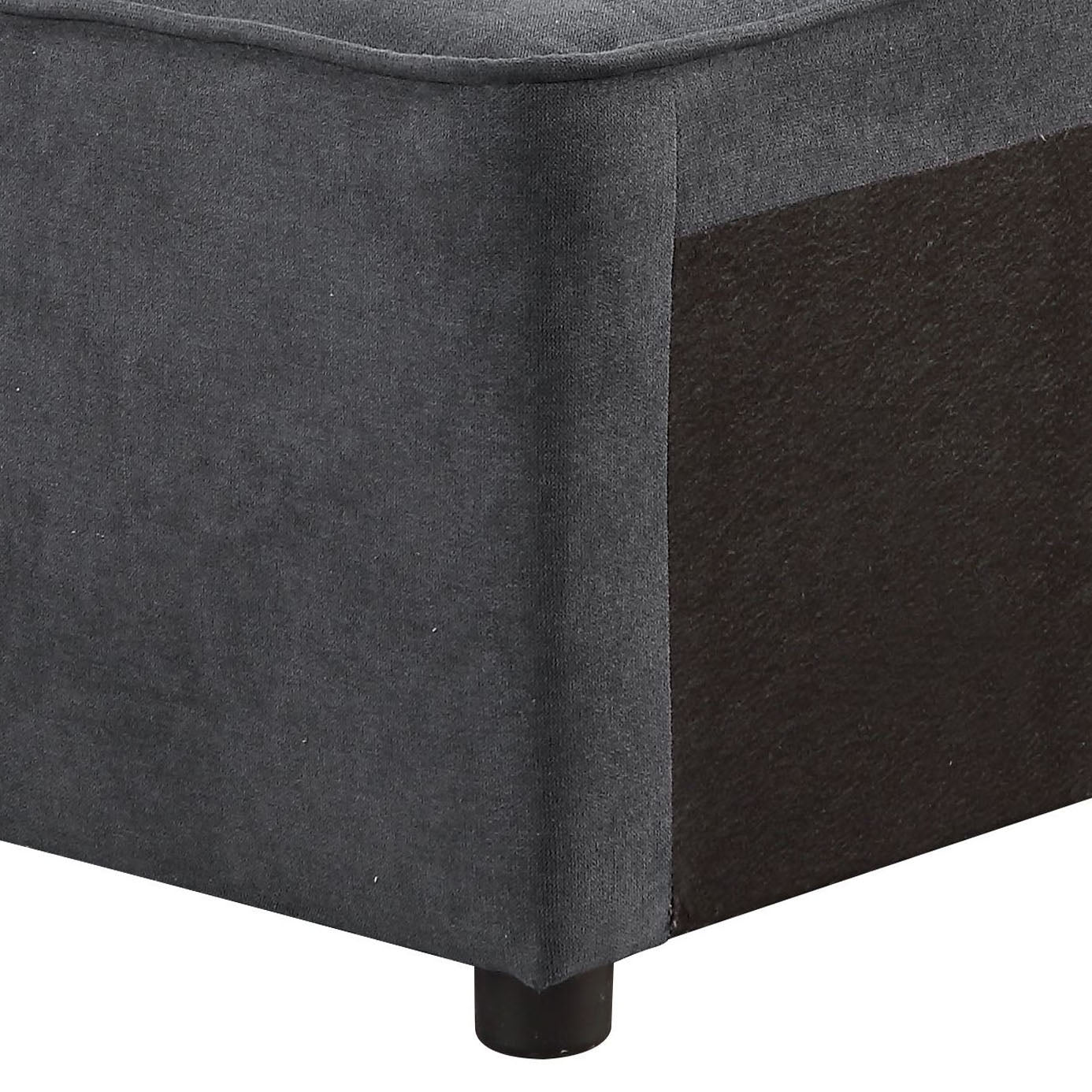 Dark grey upholstered ottoman corner with a visible dark brown fabric panel and short black leg