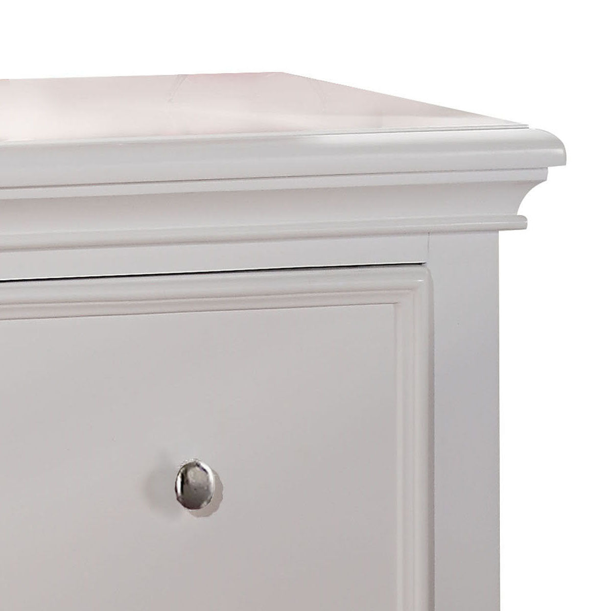Closeup of white dresser top with decorative molding and silver drawer pull