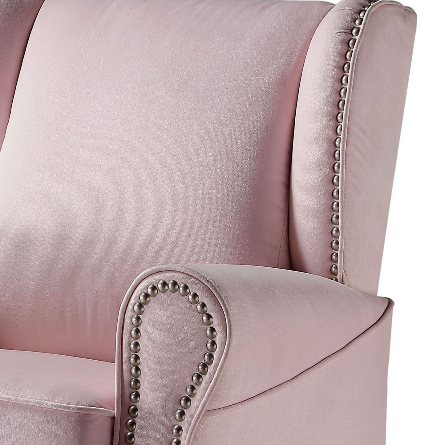 Closeup of a pink velvet wingback chair with silver nailhead trim detail