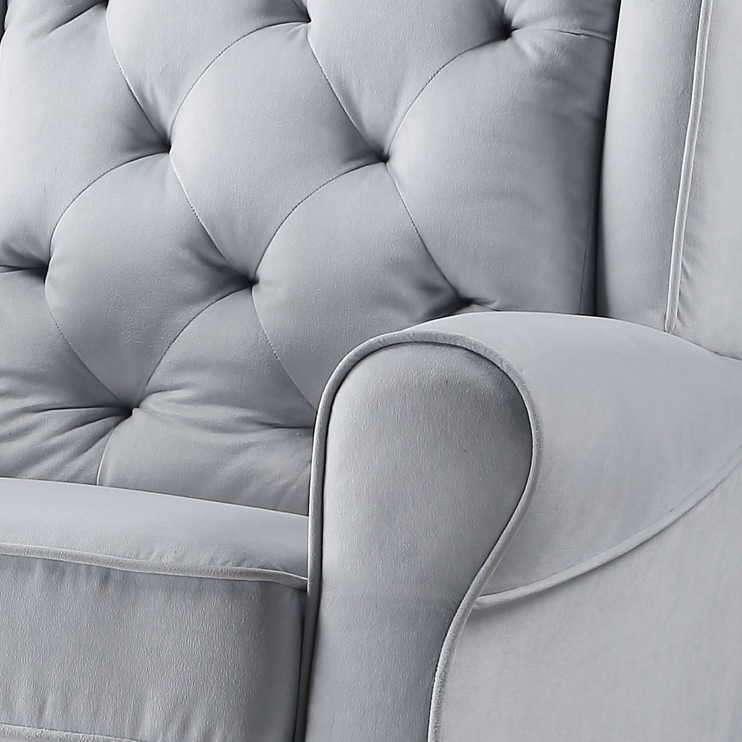 Grey velvet armchair with elegant button tufting on the back and smooth armrest