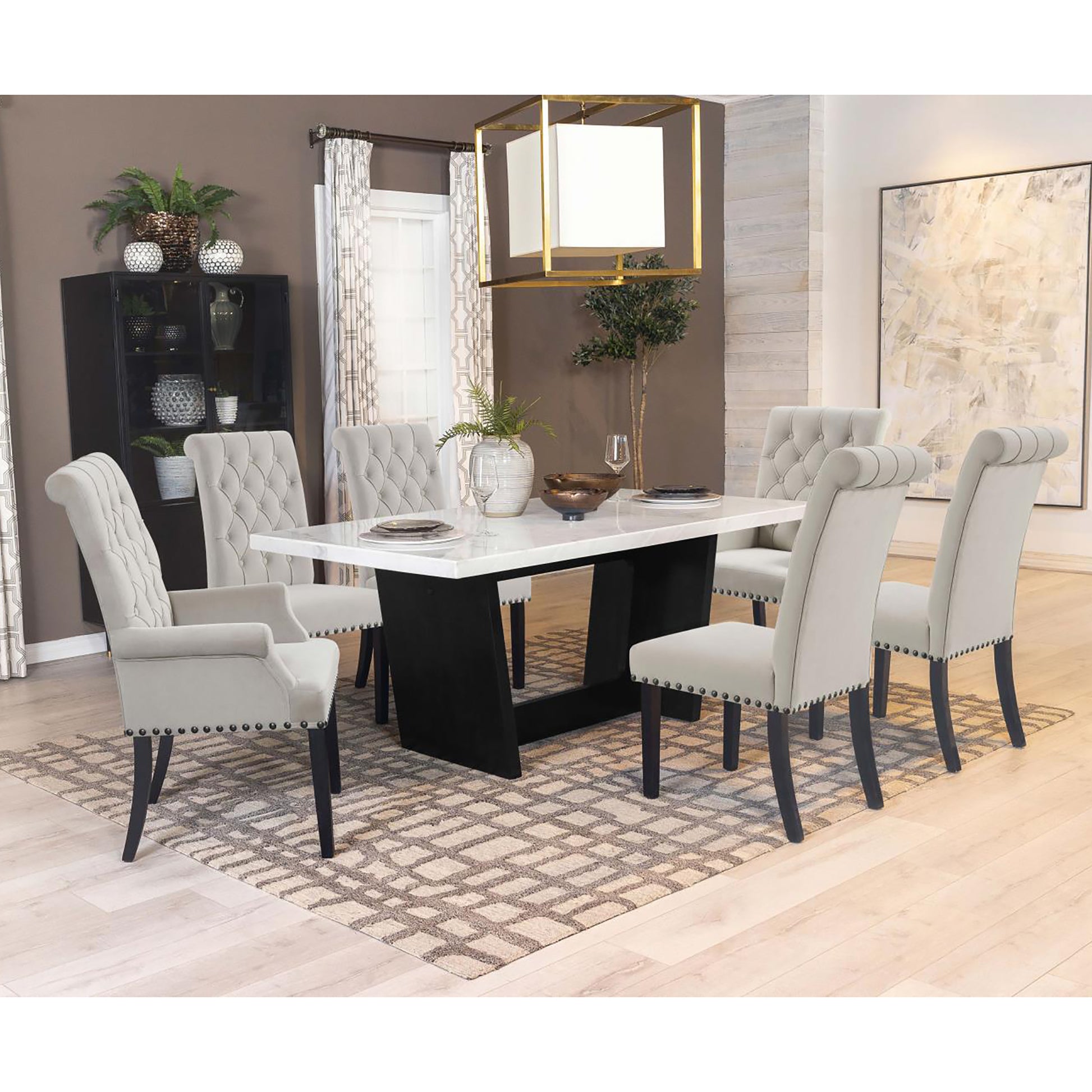 Tufted grey upholstered dining chairs surrounding a white marbletop dining table with a black pedestal base