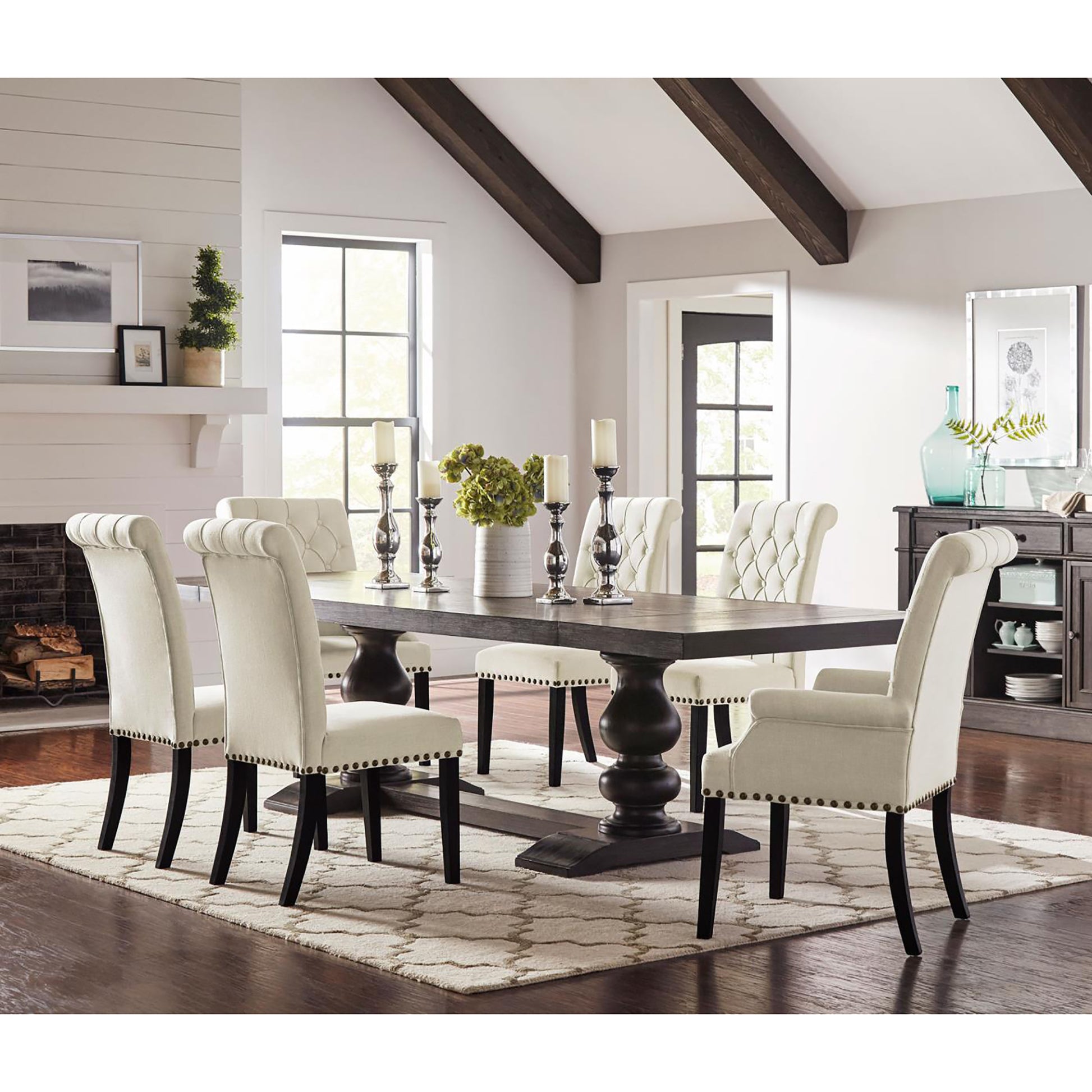 Tufted cream dining chairs with nailhead trim complement a dark wood pedestal dining table