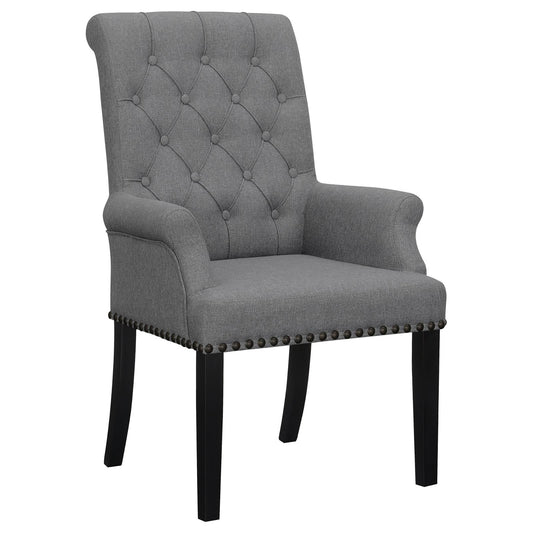 Tufted grey fabric accent chair with rolled arms and nailhead trim on dark wood legs