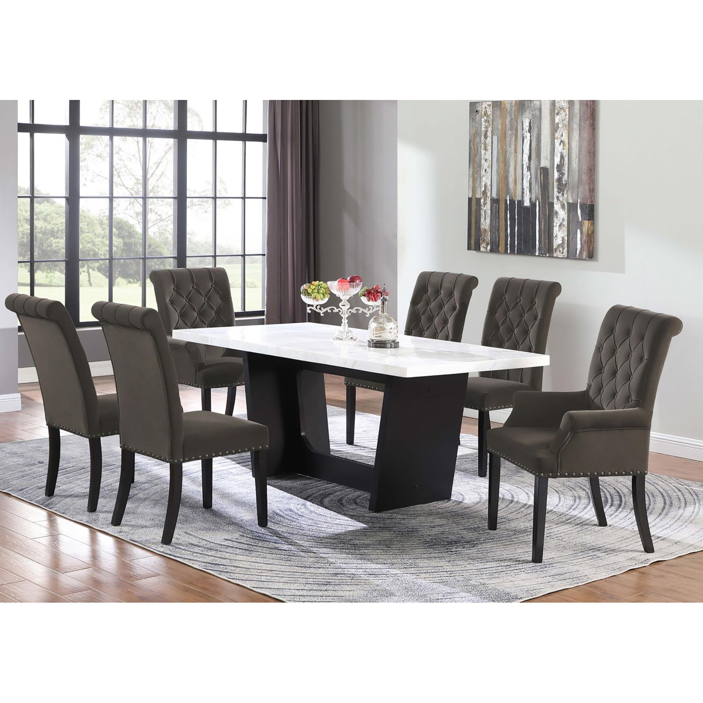 Tufted grey fabric dining chairs with nailhead trim surrounding a white marbletop dining table with dark wood base