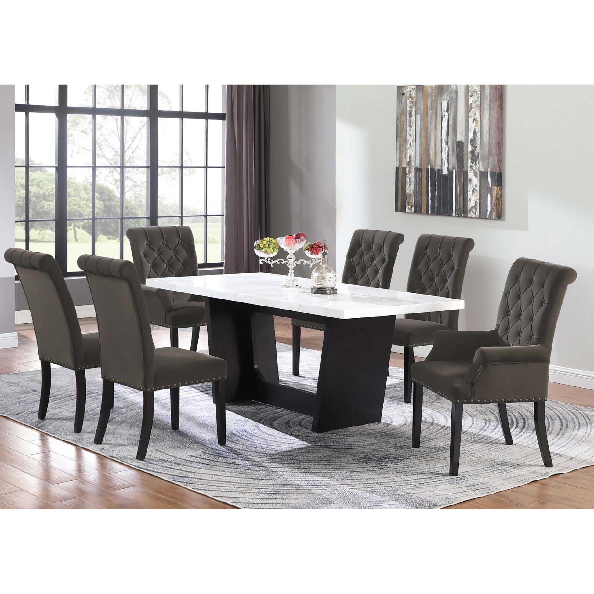 Tufted grey fabric dining chairs with nailhead trim surrounding a white marbletop dining table with dark wood base