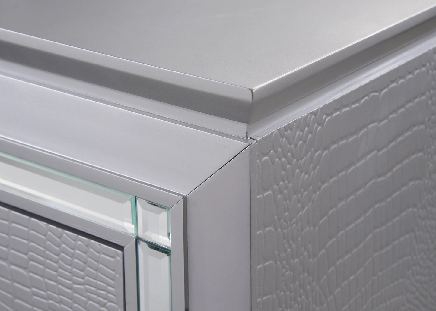 Closeup of a silver embossed dresser drawer with mirrored trim highlighting its textured finish
