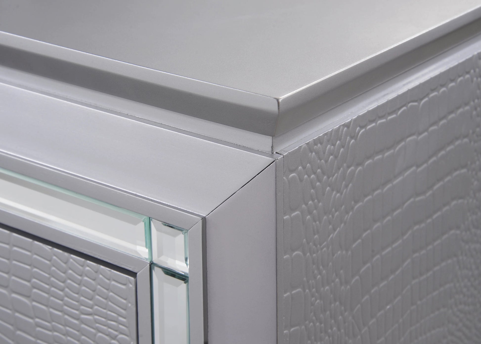 Closeup of a silver embossed dresser drawer with mirrored trim highlighting its textured finish