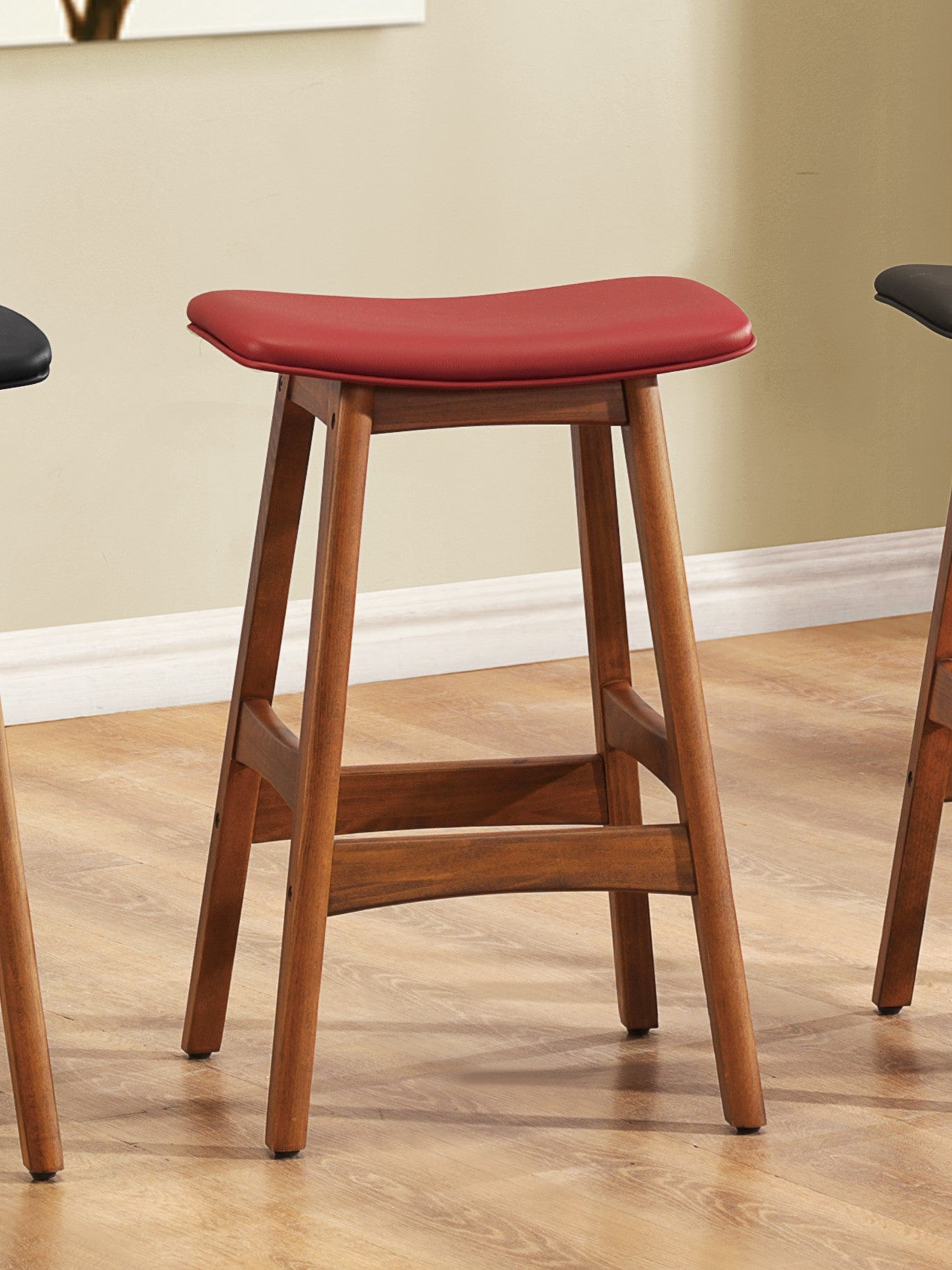 Red saddle stool with a natural wood frame and footrest