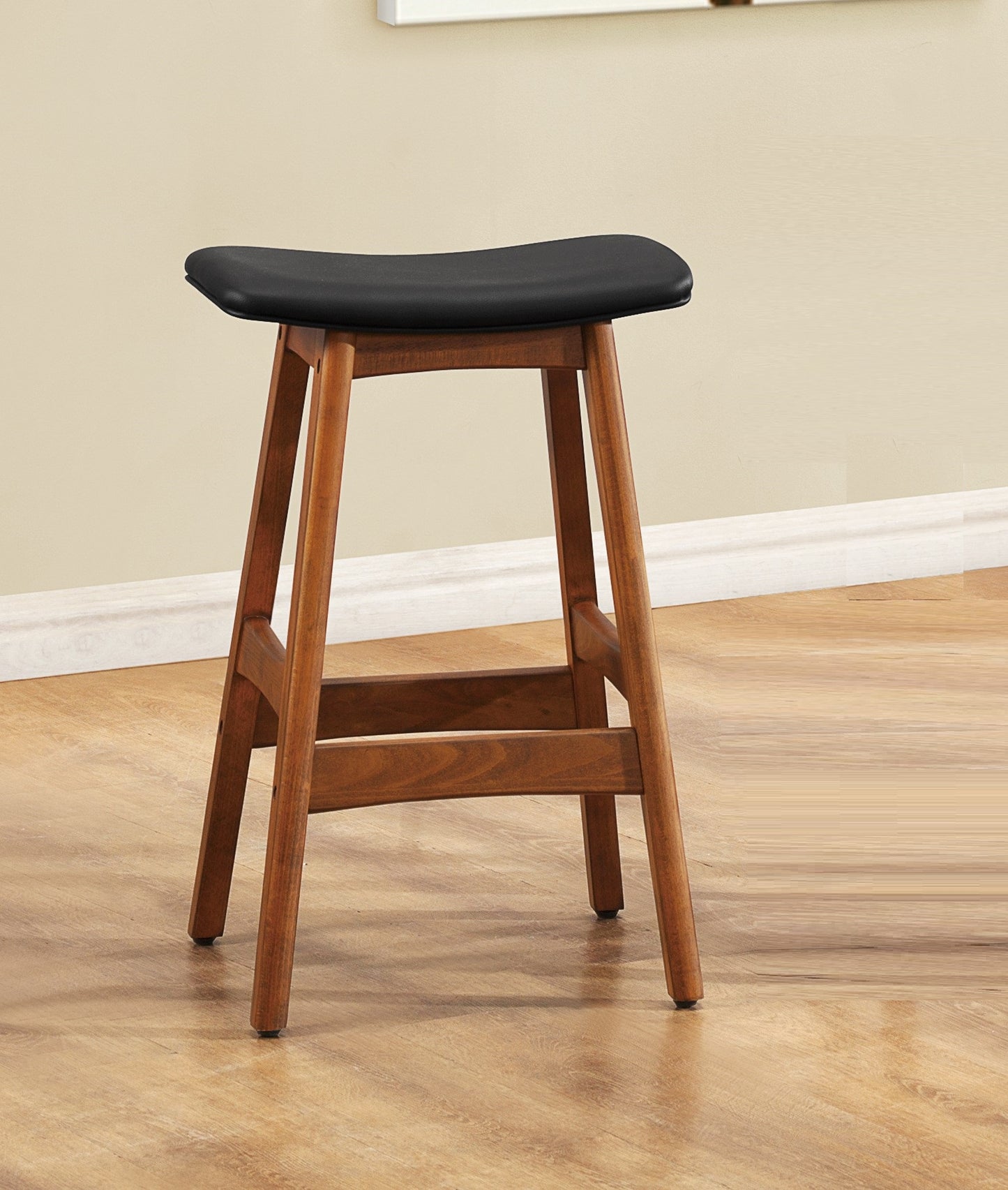 Saddleshaped counter stool with a black upholstered seat and warm wood base