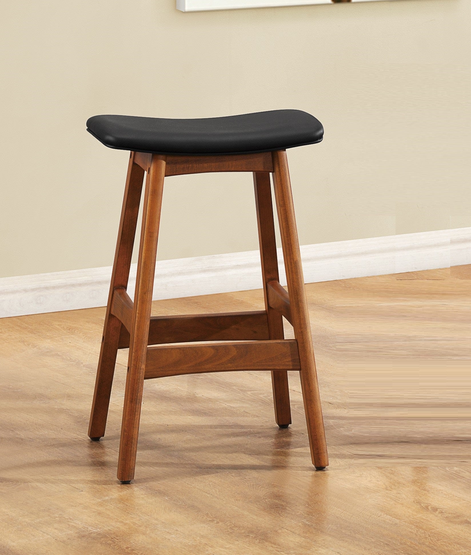 Saddleshaped counter stool with a black upholstered seat and warm wood base