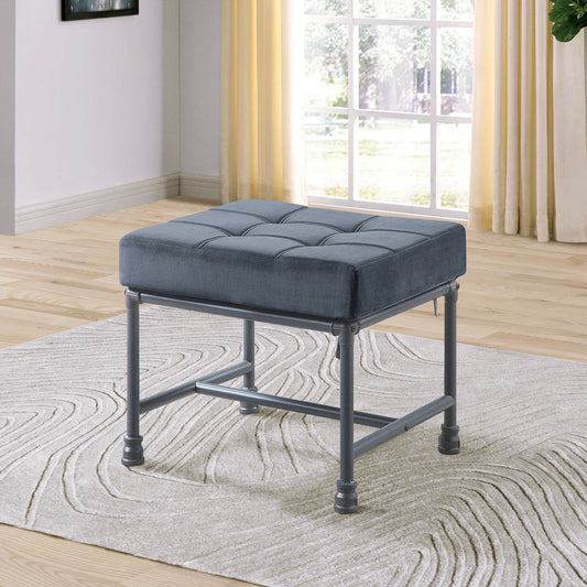 Dark grey velvet upholstered ottoman with button tufting and metal frame