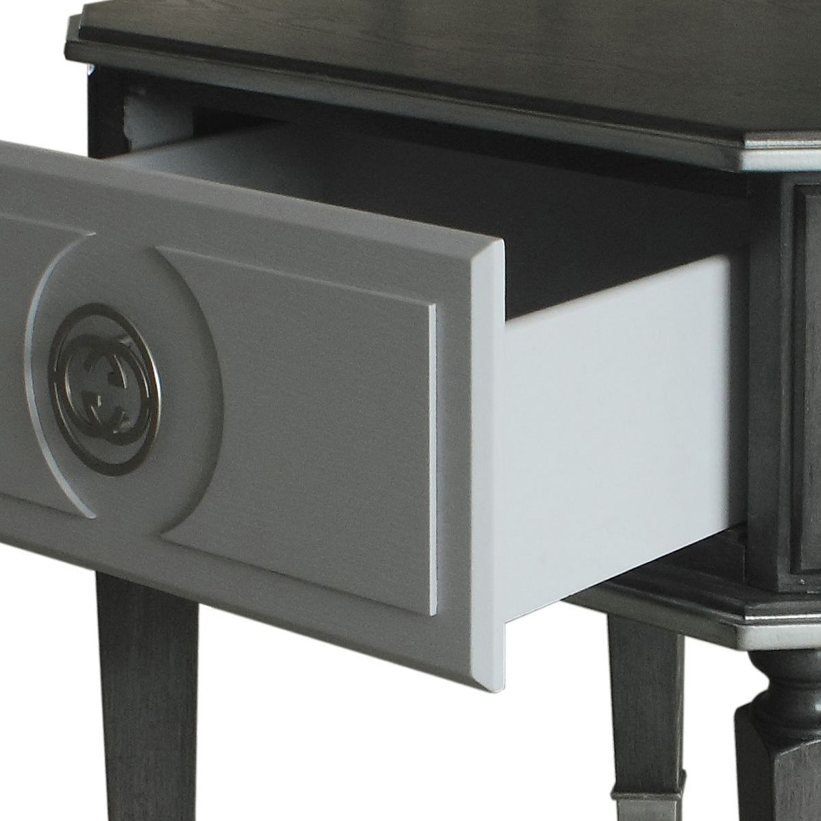 Gray nightstand drawer with interlocking G logo pull and open compartment