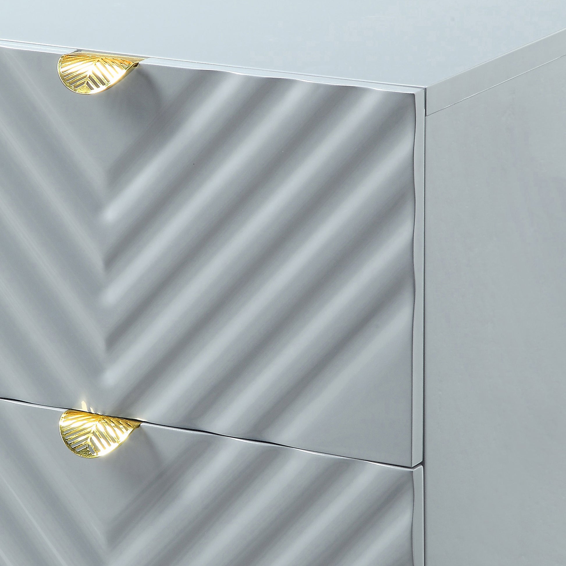 Gray dresser with textured front featuring ornate gold leaf drawer pulls