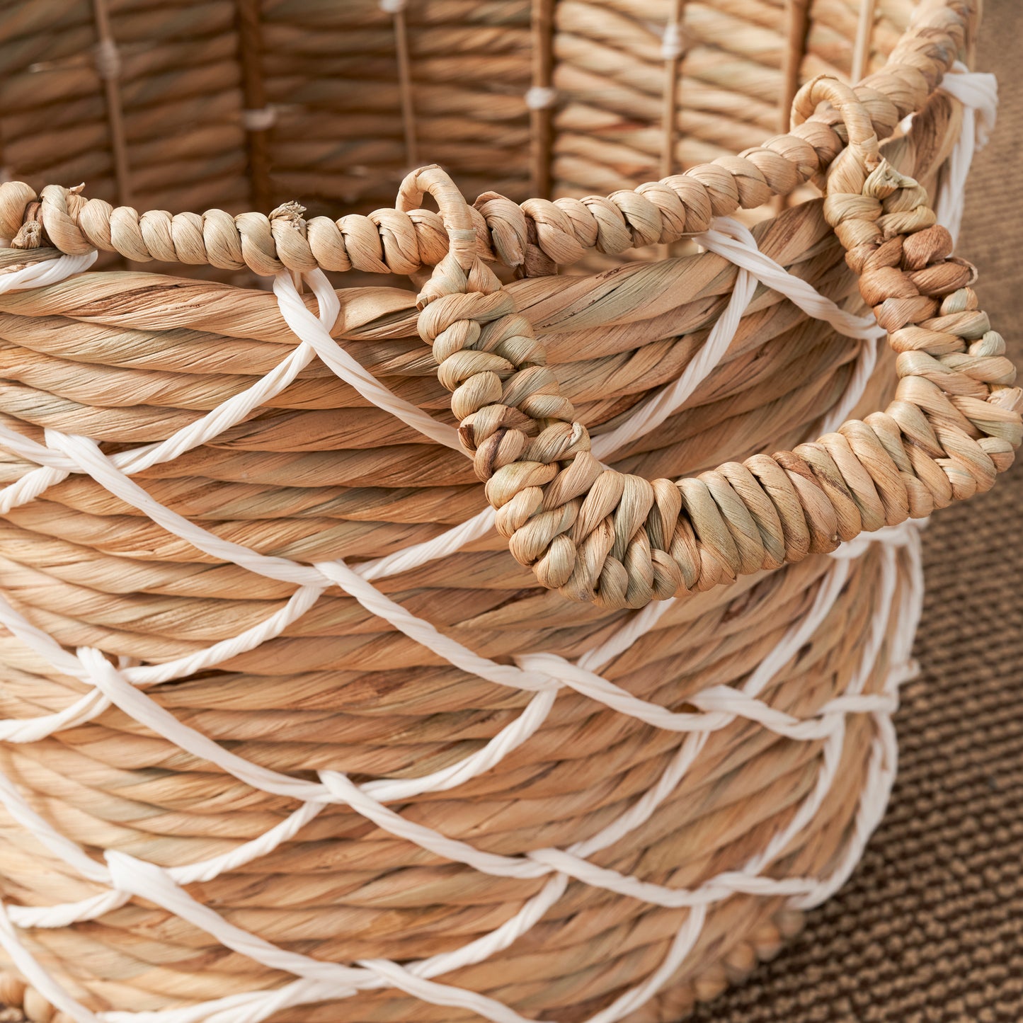 Woven natural fiber basket with white net detail and rope handles