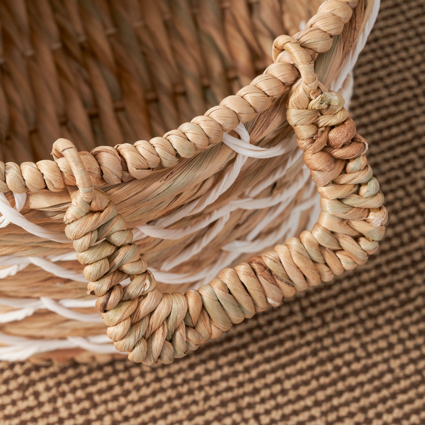 Natural fiber woven basket with braided handles and white accent