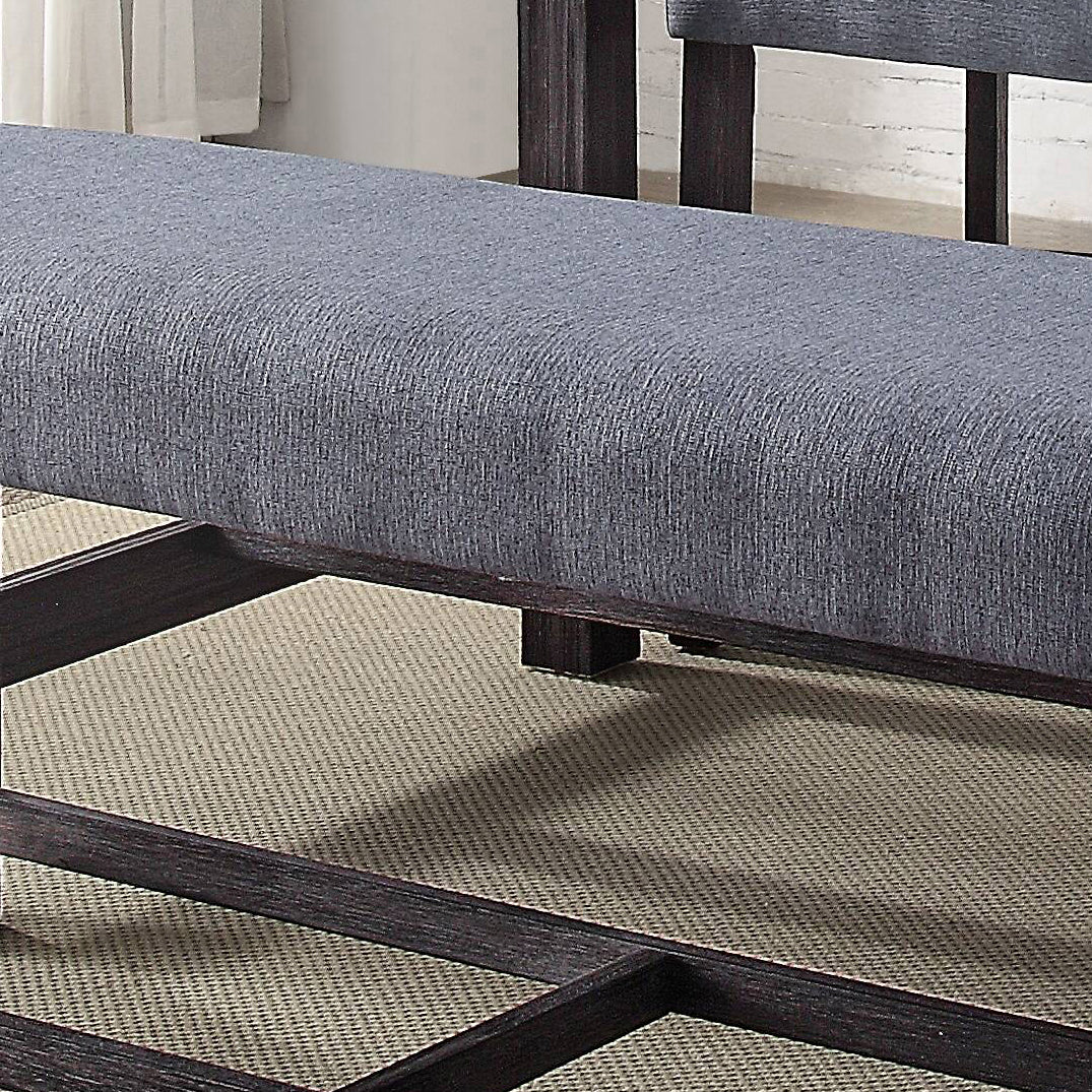 Gray upholstered dining bench with dark wood frame on a textured rug