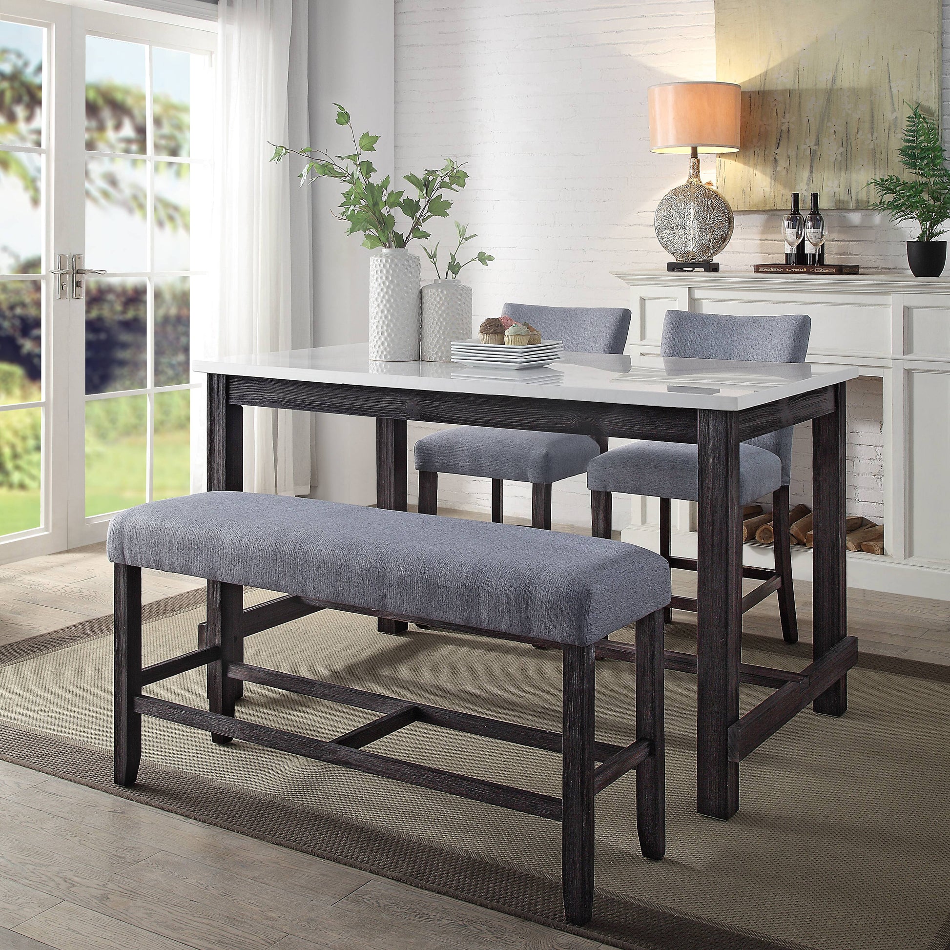 Dark wood counter height table with white marble top and upholstered bench for seating