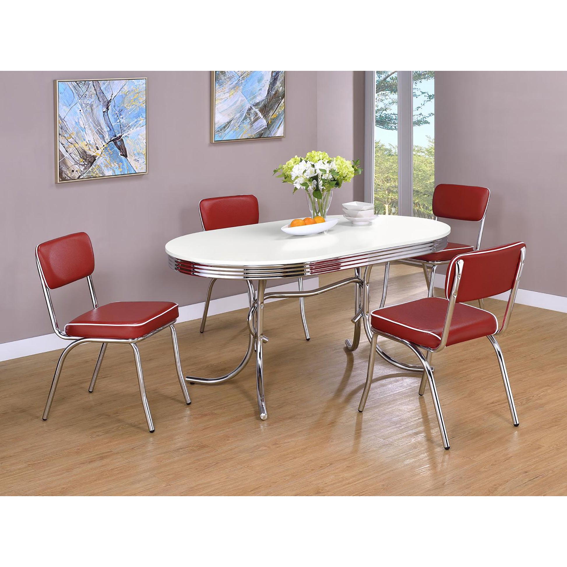 Retro red diner chairs with white piping surround a white oval table with chrome accents