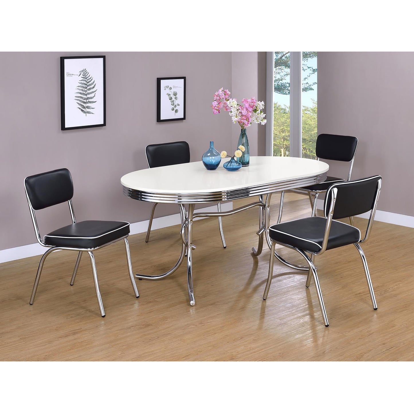 Retro oval white dining table with four black vinyl chairs featuring chrome accents