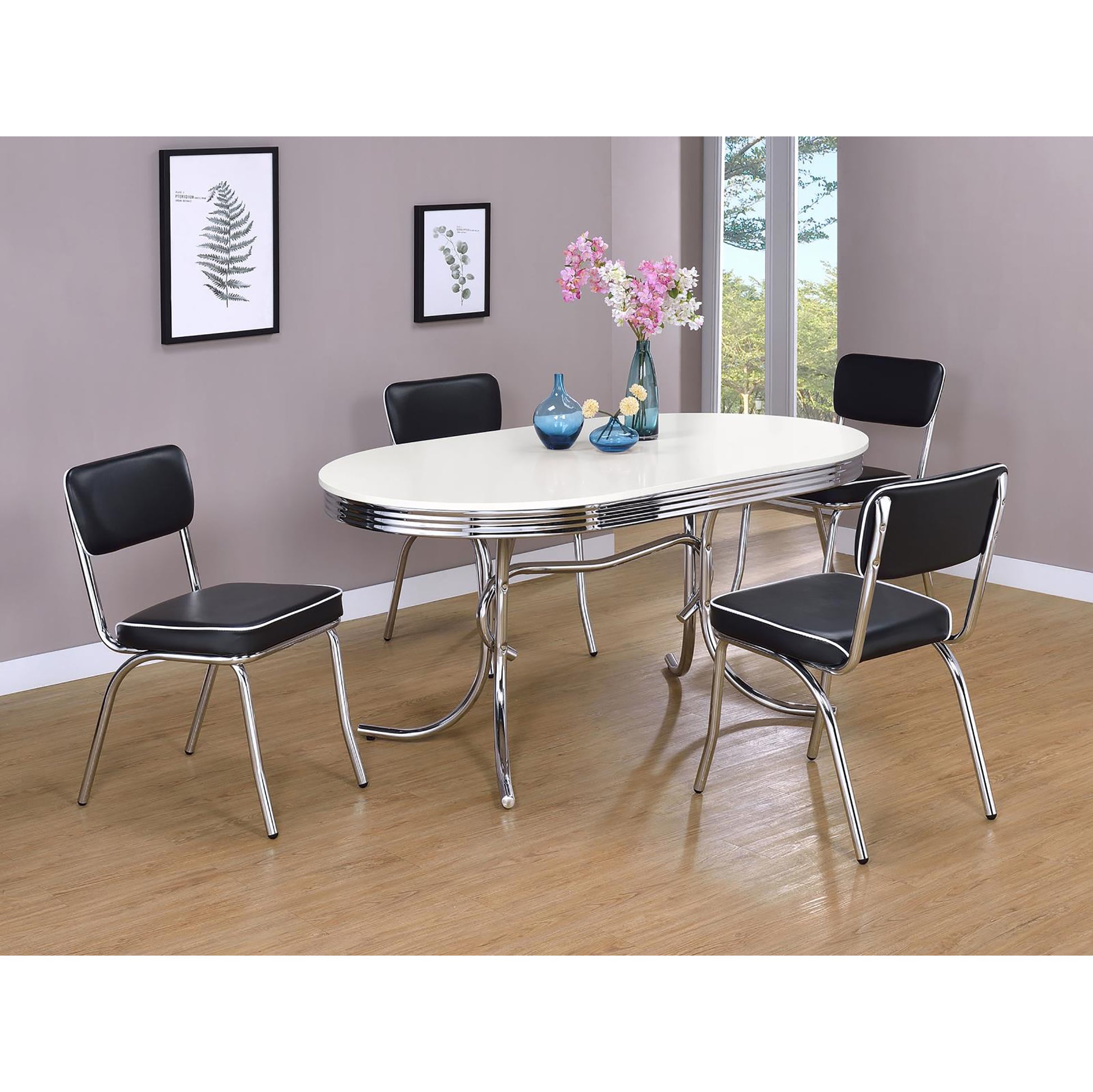Retro oval white dining table with four black vinyl chairs featuring chrome accents