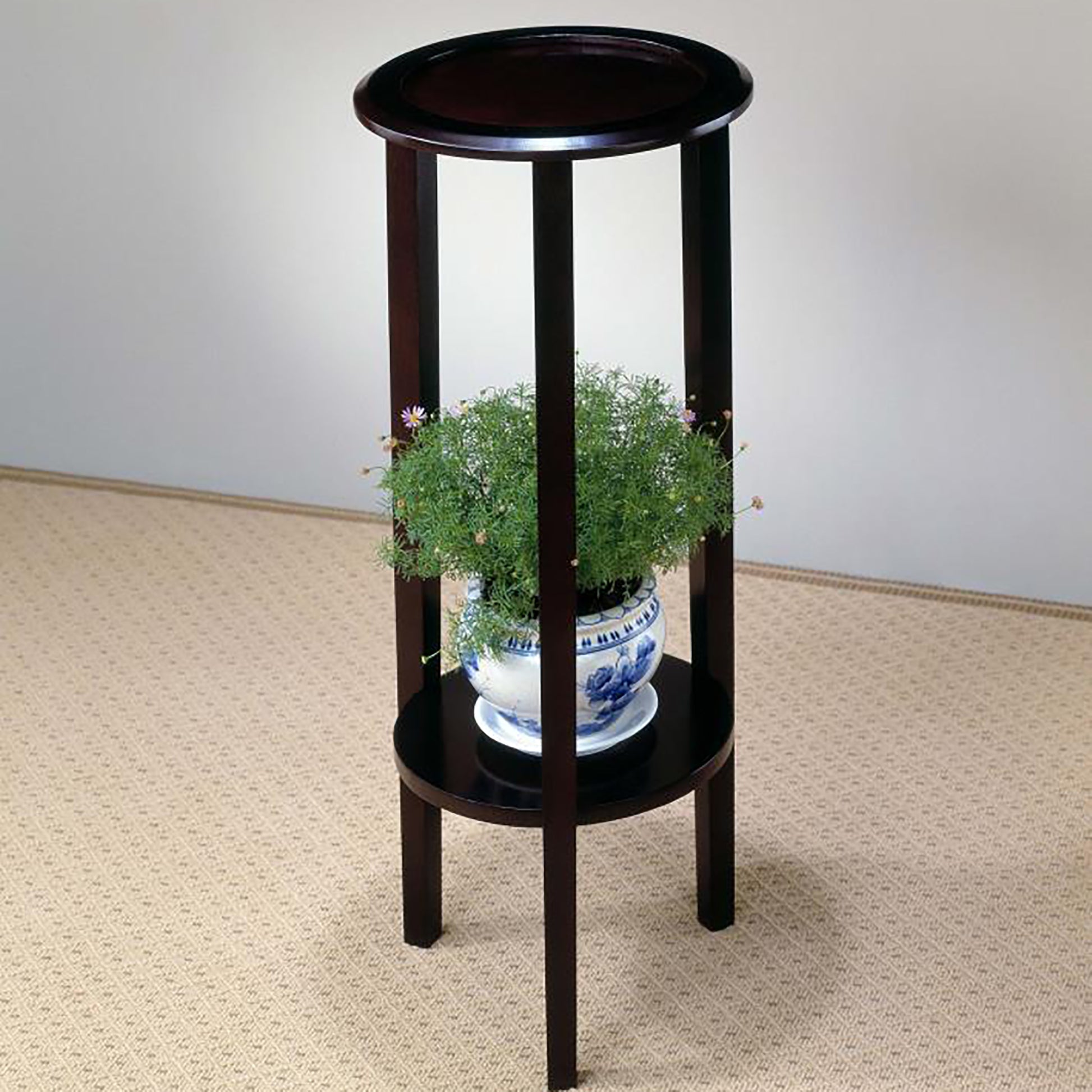 Dark wood plant stand with two circular shelves holding a potted green plant
