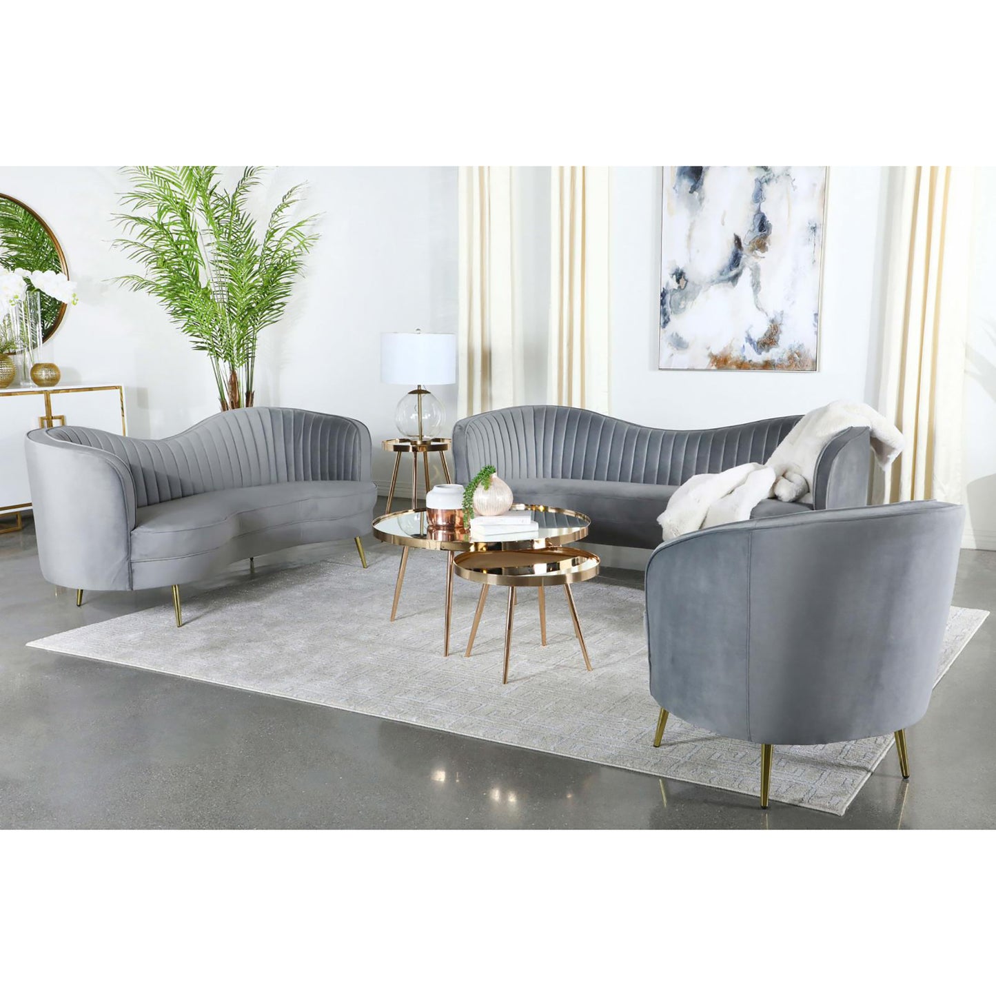 Elegant grey velvet curved sofa with plush channeling and gold legs perfect for living rooms