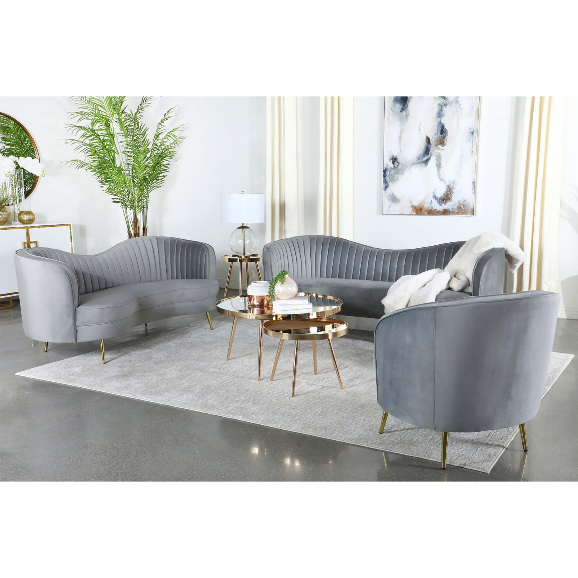 Elegant grey velvet curved sofa with plush channeling and gold legs perfect for living rooms