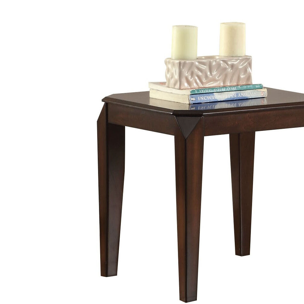 Dark wood end table with angled legs and stacked books candles and decorative item