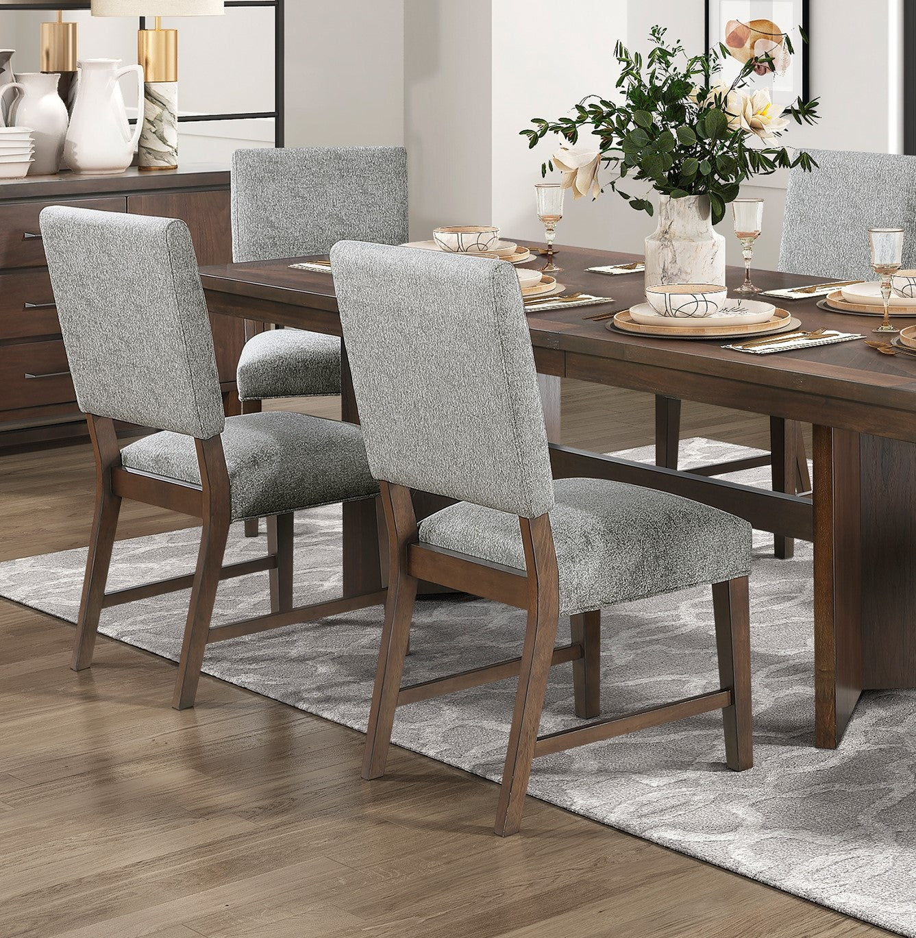 Grey upholstered dining chairs with wooden frames arranged around a dark wood table