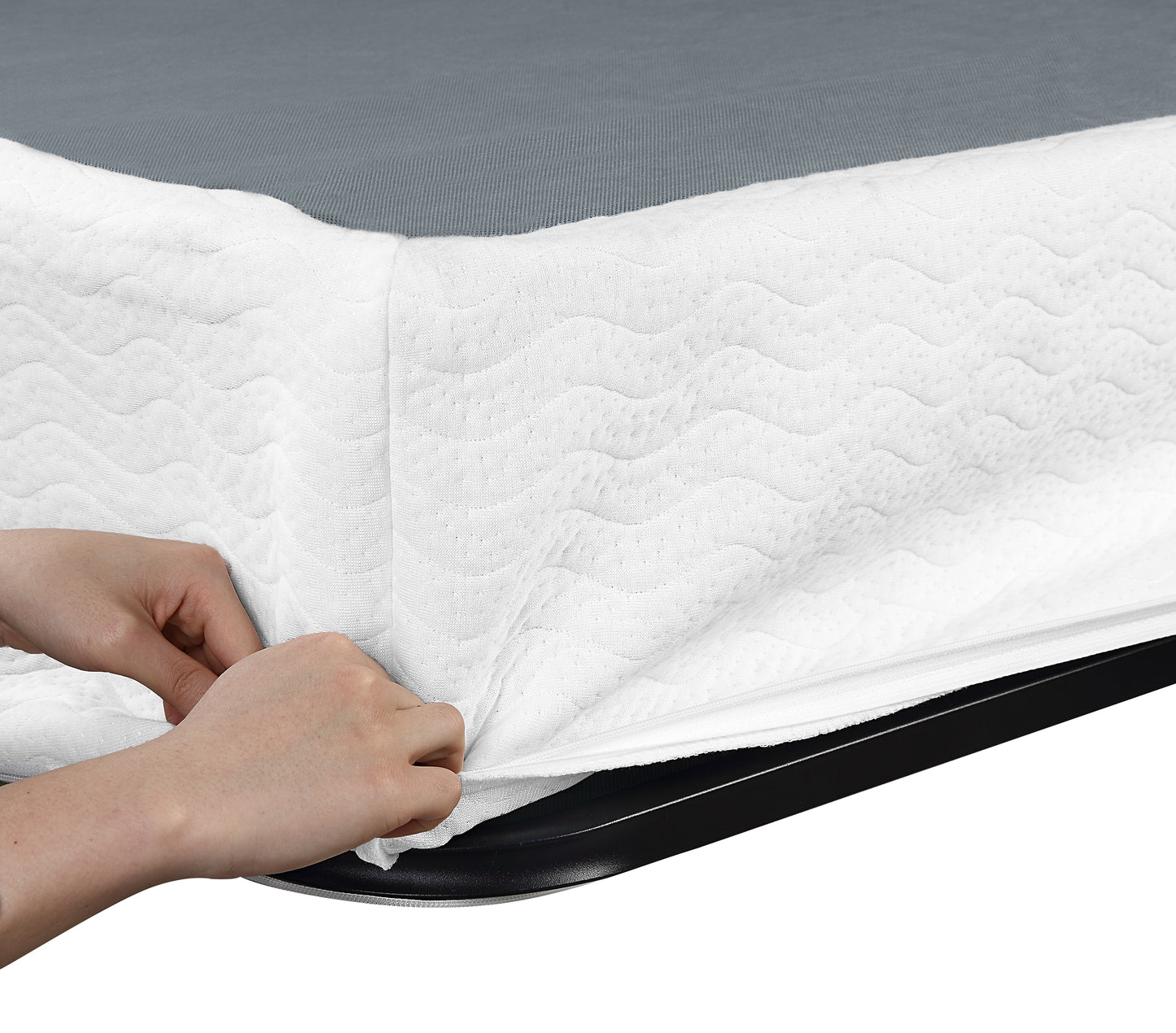 Hands zipping a white quilted mattress protector onto a grey base