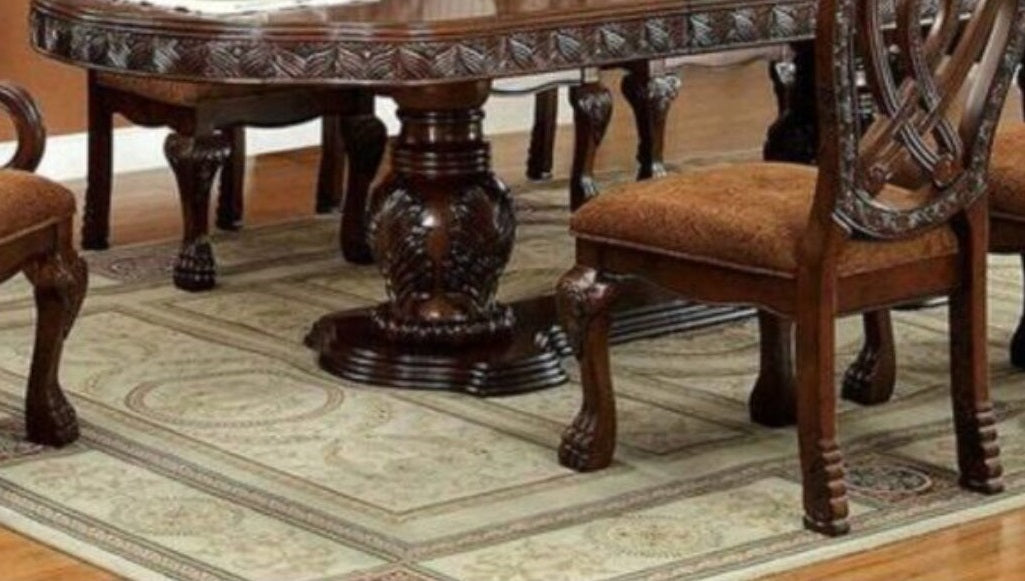 Mahogany dining table with ornate carvings on base and chairs