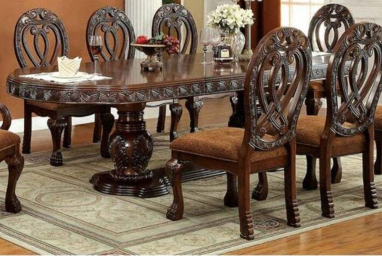 Ornate dark wood dining table with carved details and matching upholstered chairs