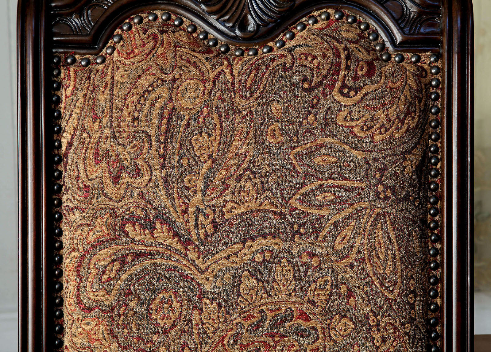 Intricately patterned tapestry fabric in gold and burgundy on a decorative dining chair