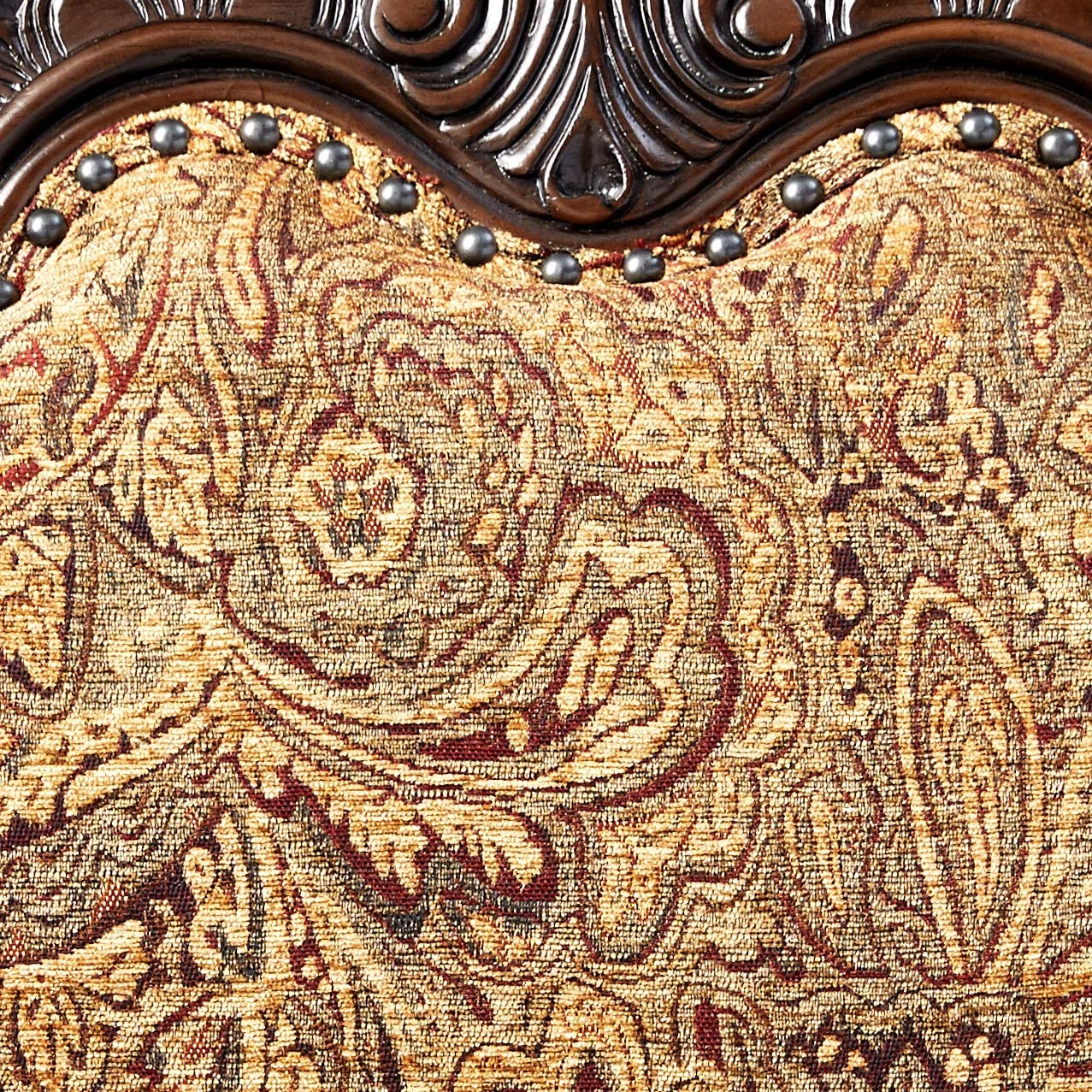Closeup of ornate paisley upholstered chair fabric with dark wood trim