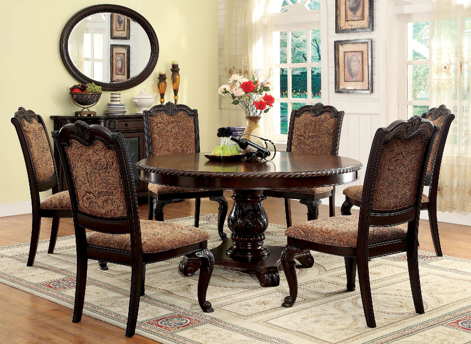 Dark wood dining table with ornate pedestal base and upholstered chairs