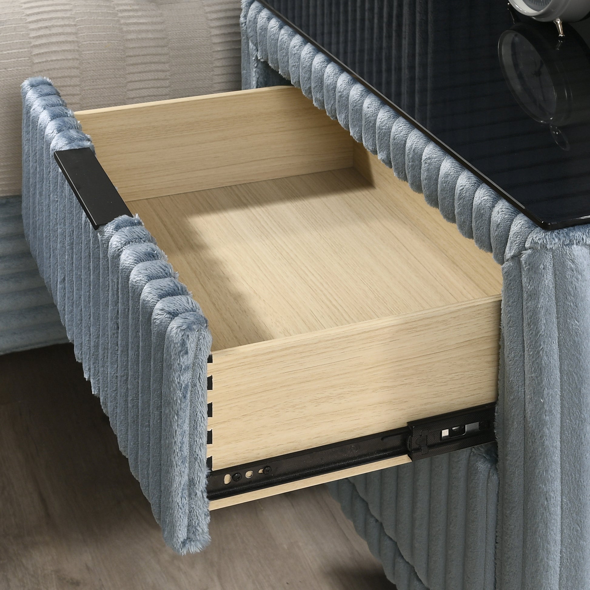 Blue corduroy nightstand with open wooden drawer and black handle
