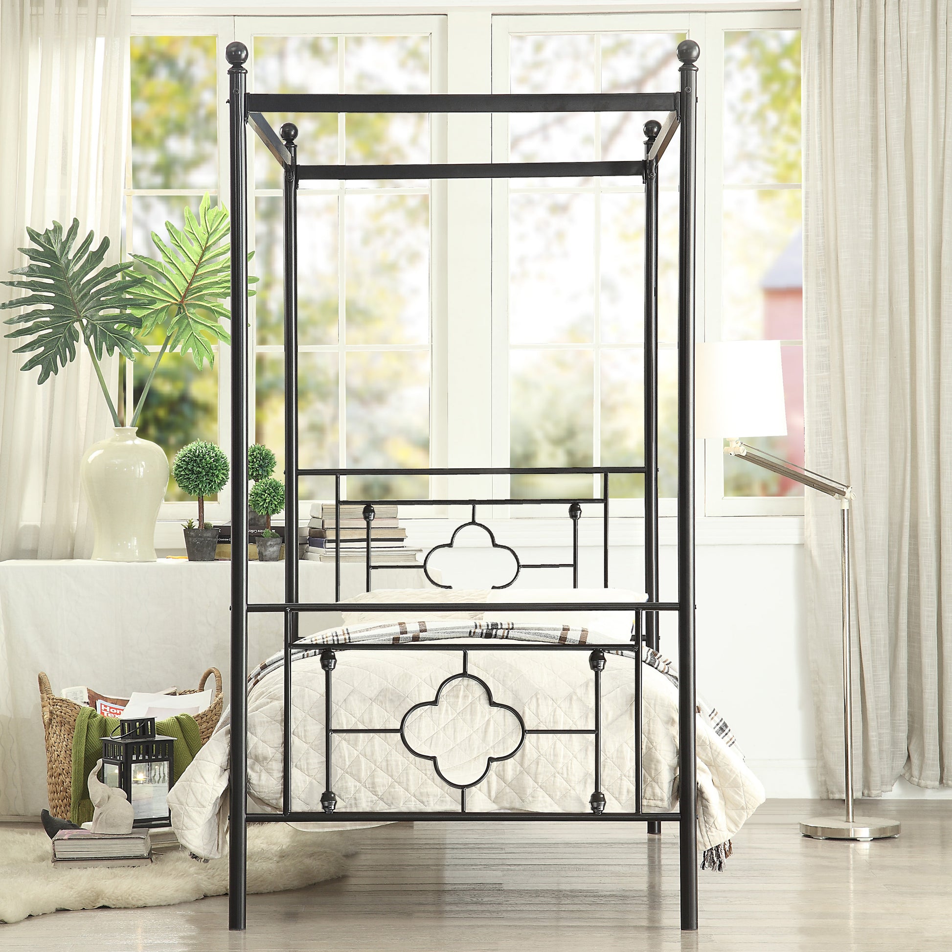 Black metal canopy bed frame with quilted bedding and decorative scrollwork headboard
