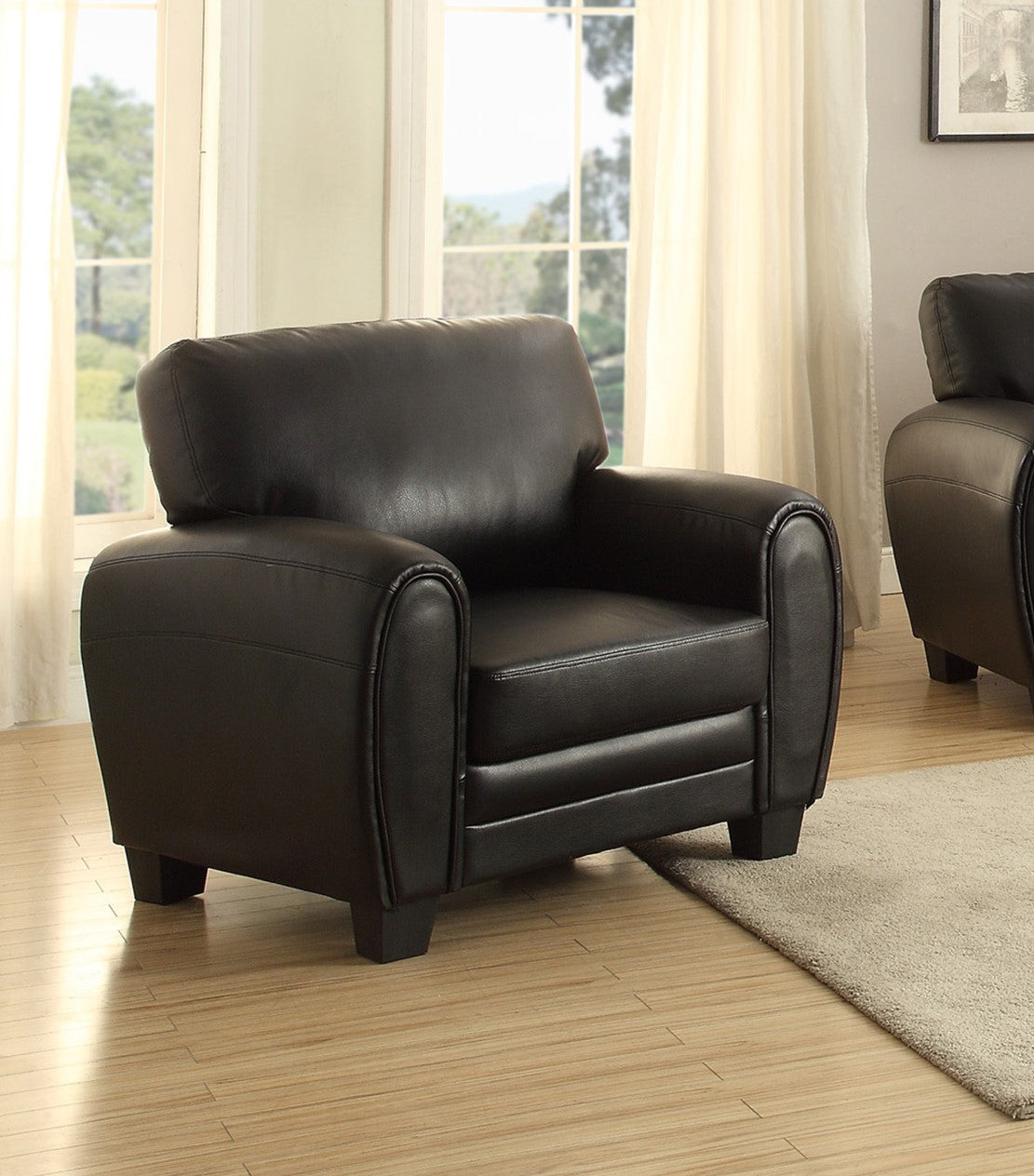 Black leather armchair with curved armrests and plush cushioning perfect for a living room