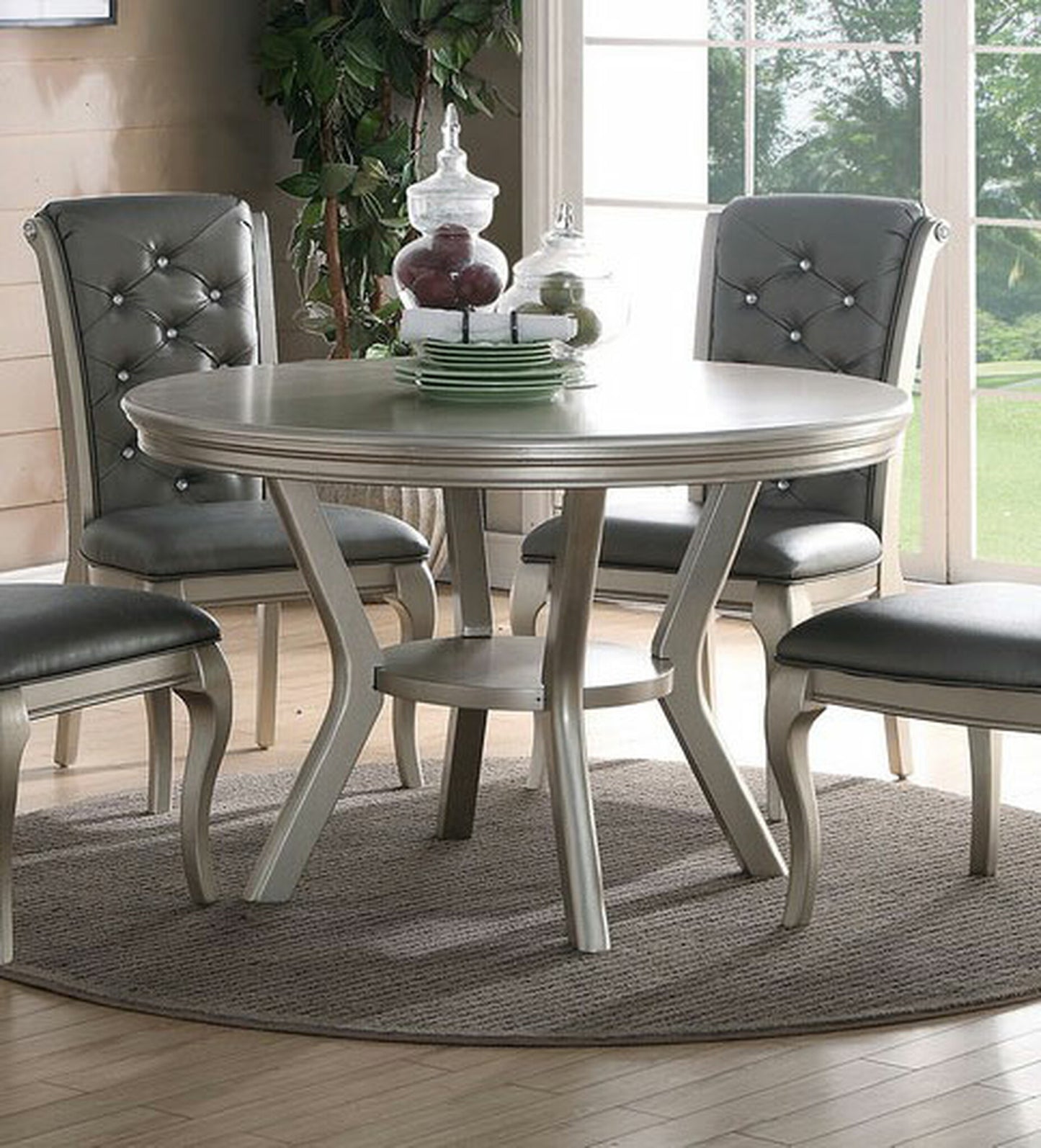 Round silver dining table with tufted gray chairs and crystal accent for elegant dining