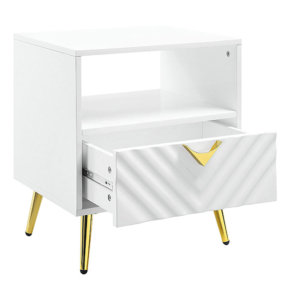 White bedside table with gold tapered legs and an open drawer featuring a chevron pattern and gold handle